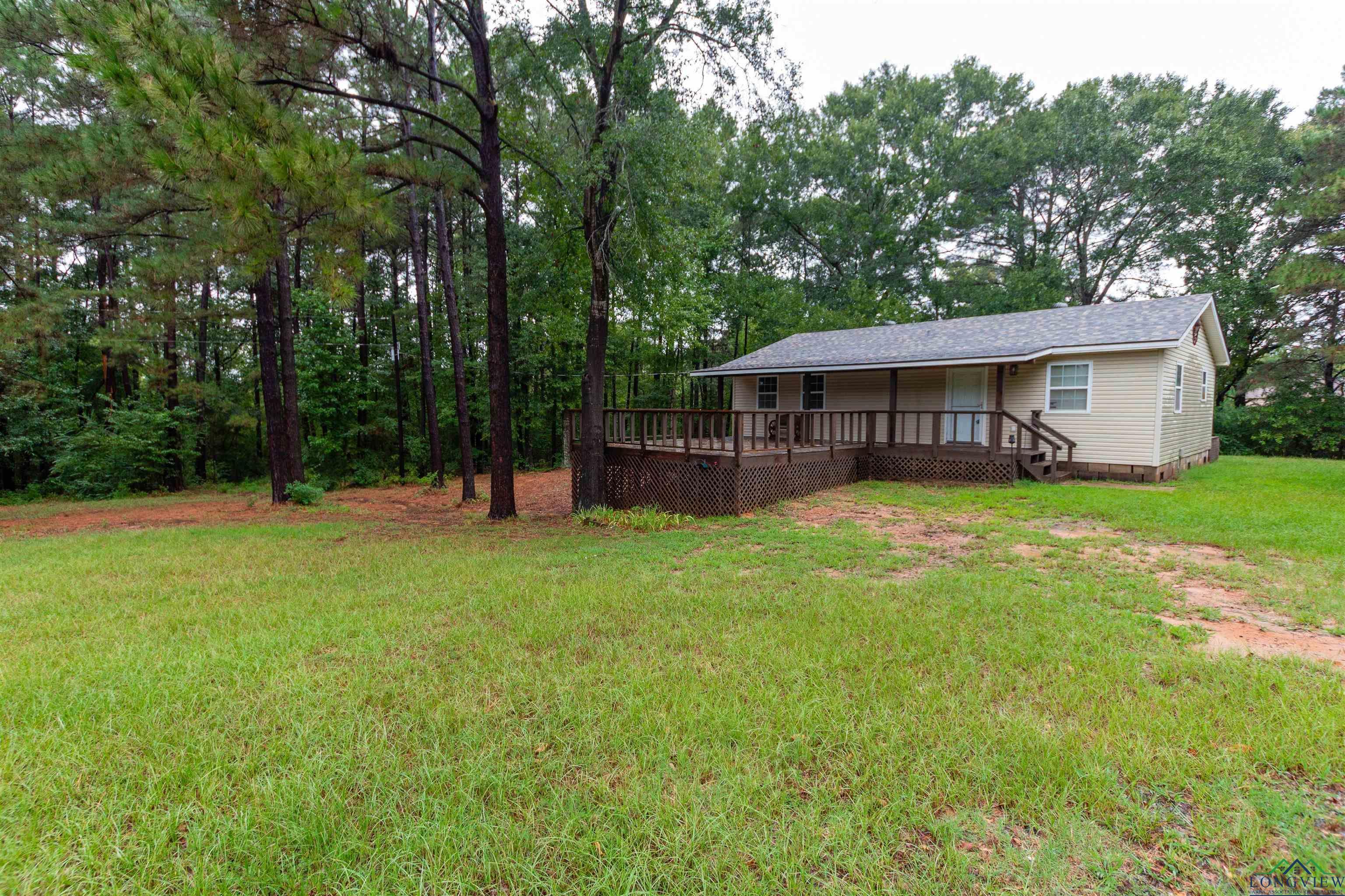 Image 2: View of grassy yard featuring covered porch and view of wooded area, Yard