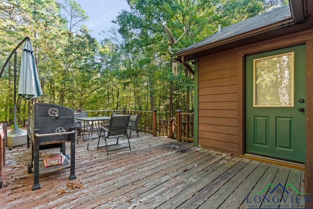 Image 3: Wooden terrace with area for grilling, outdoor dining space, and view of scattered trees, Deck