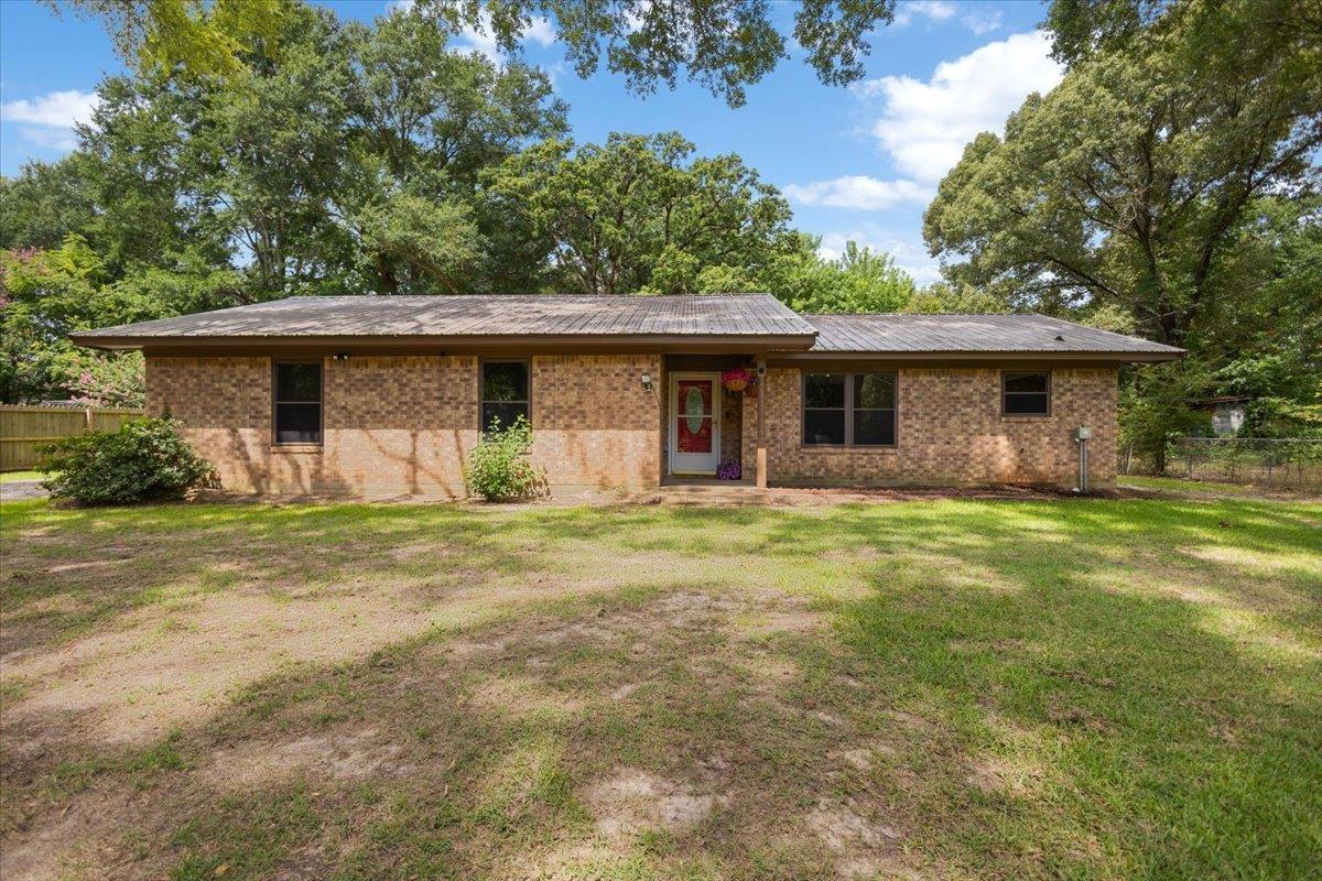 Image 0: Brick exterior featuring a covered entry, established landscaping, and a fenced perimeter, Front Of Structure