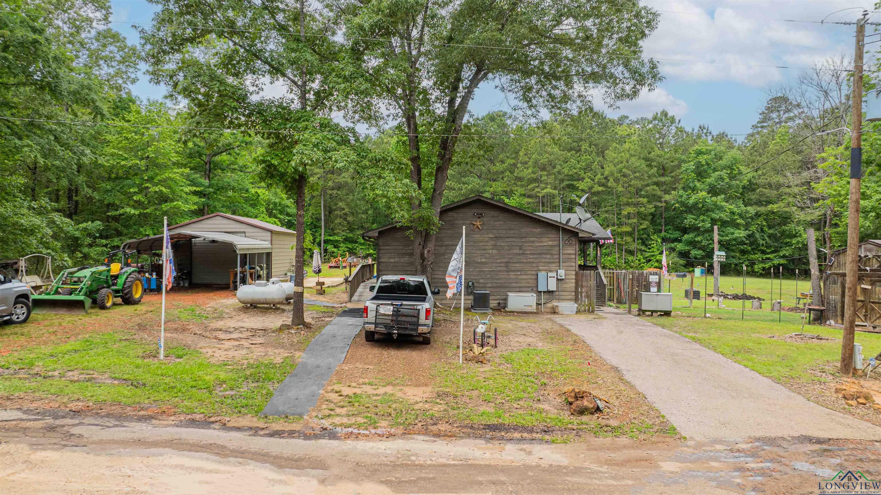 Image 1: Exterior space featuring a detached carport and aphalt driveway, Front Of Structure