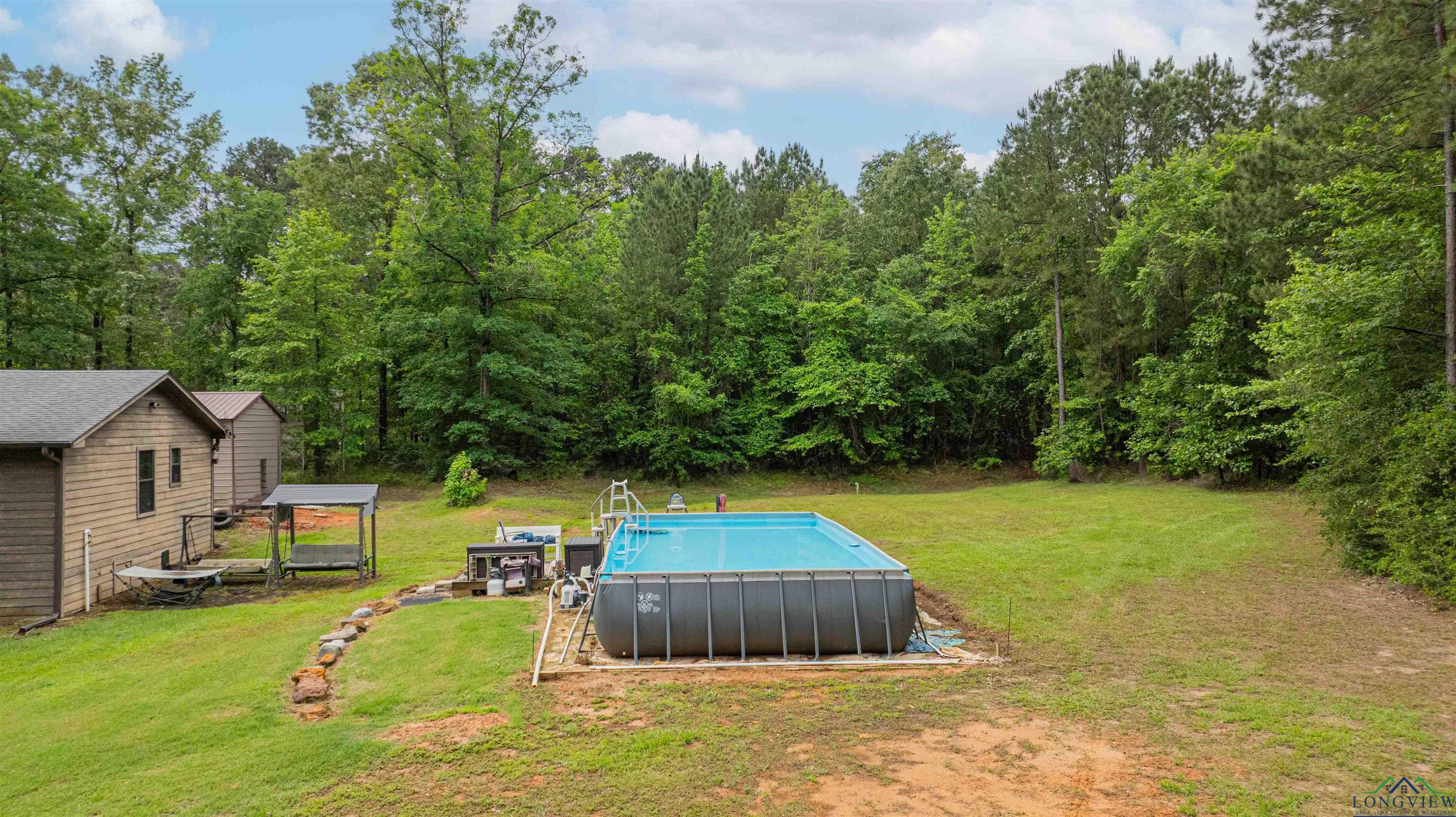 Image 3: Outdoor pool with a lawn and a view of trees, Pool