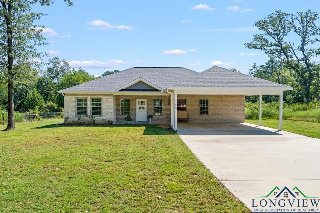 Image 0: View of front facade featuring a front yard, a shingled roof, a carport, driveway, and brick siding, Front Of Structure