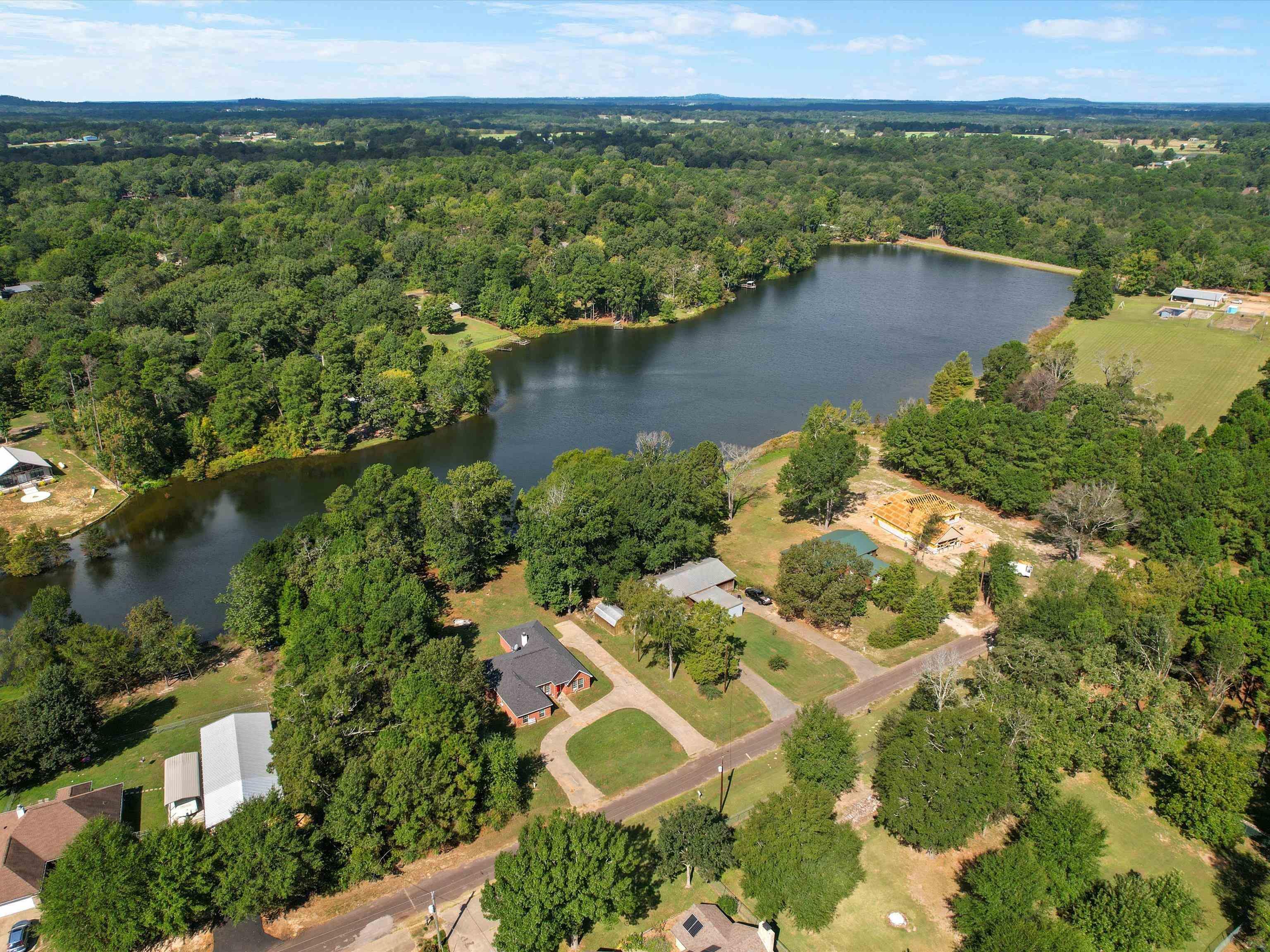 Image 3: Aerial view of property's location featuring a nearby body of water and a heavily wooded area, Aerial View