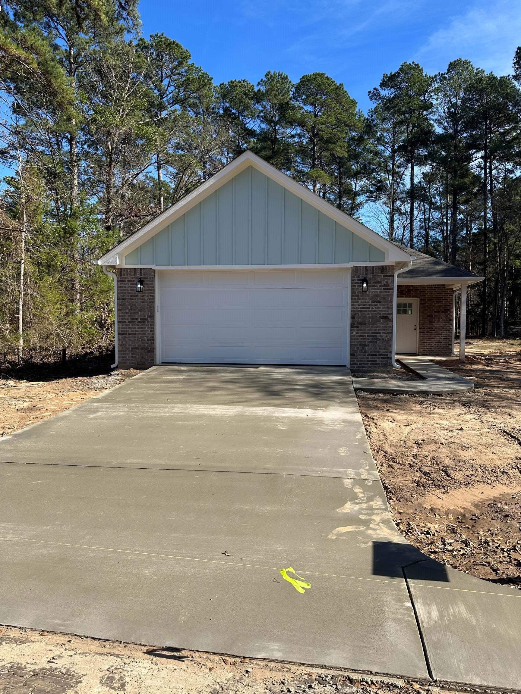 Image 0: View of front of house featuring brick siding, board and batten siding, concrete driveway, and an attached garage, Front Of Structure