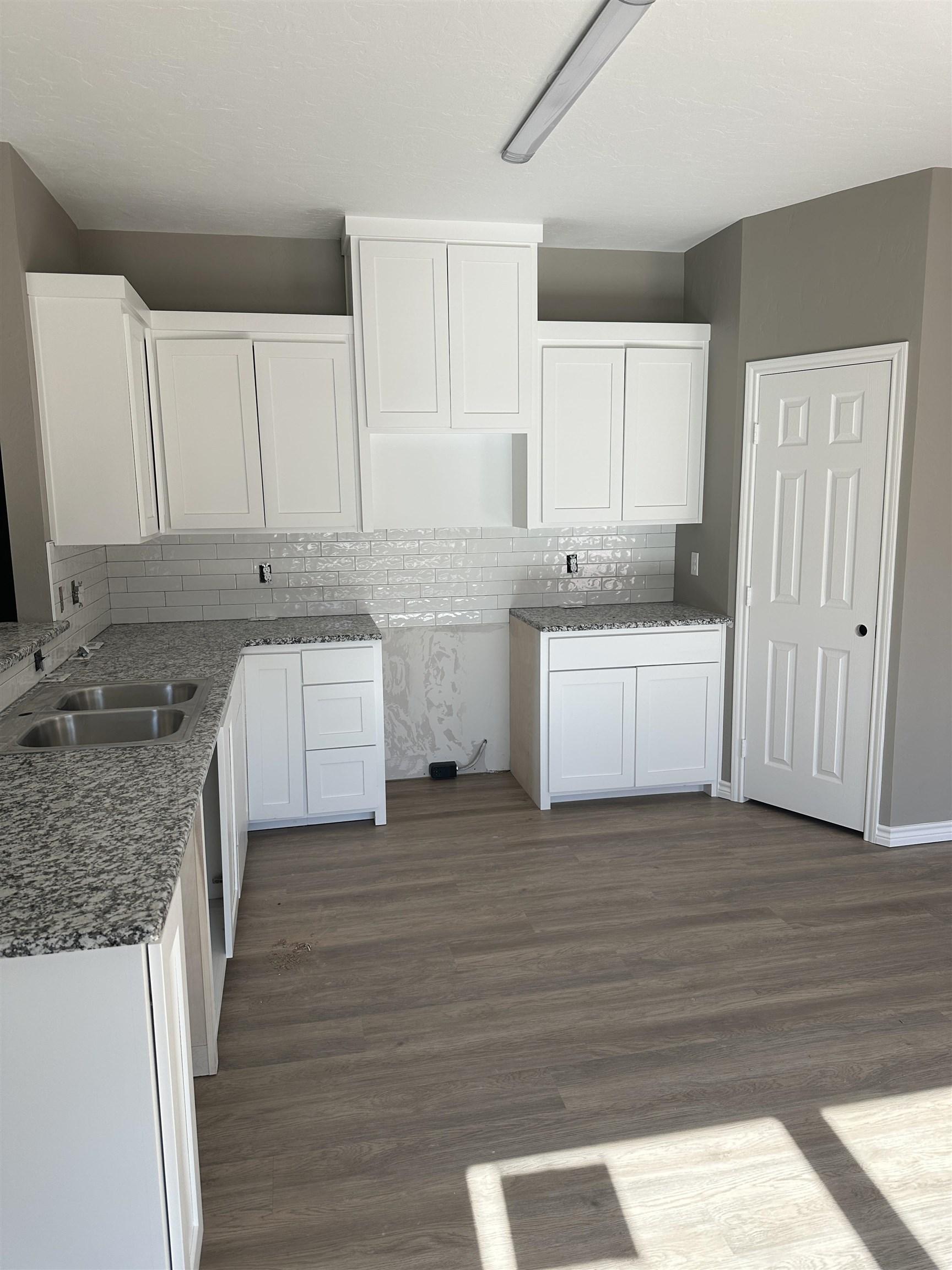 Image 1: Kitchen featuring white cabinetry, dark wood-style flooring, tasteful backsplash, and dark stone counters, Kitchen