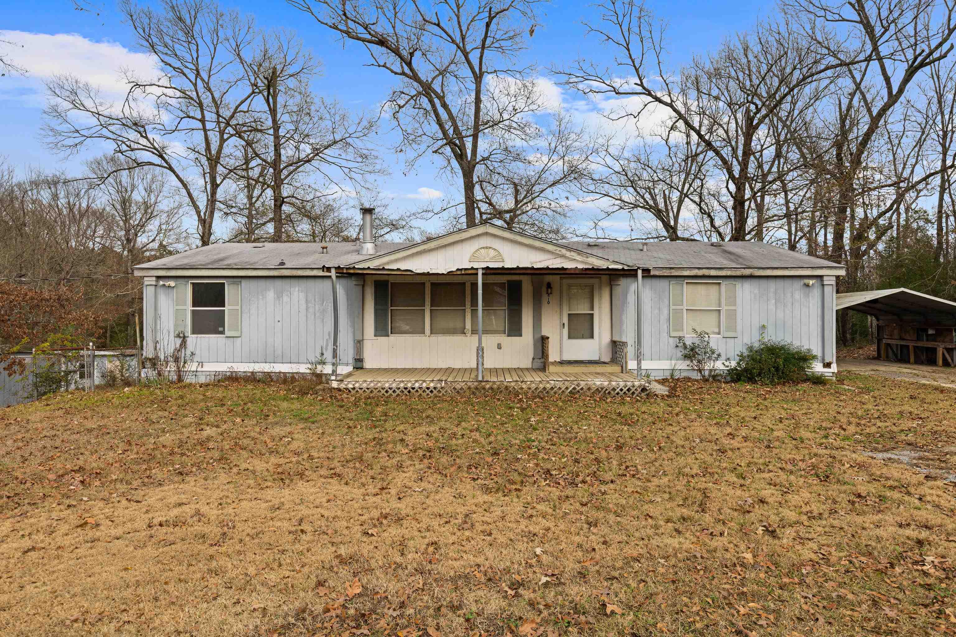 Image 1: Single story home with a front yard, covered porch, and a detached carport, Front Of Structure