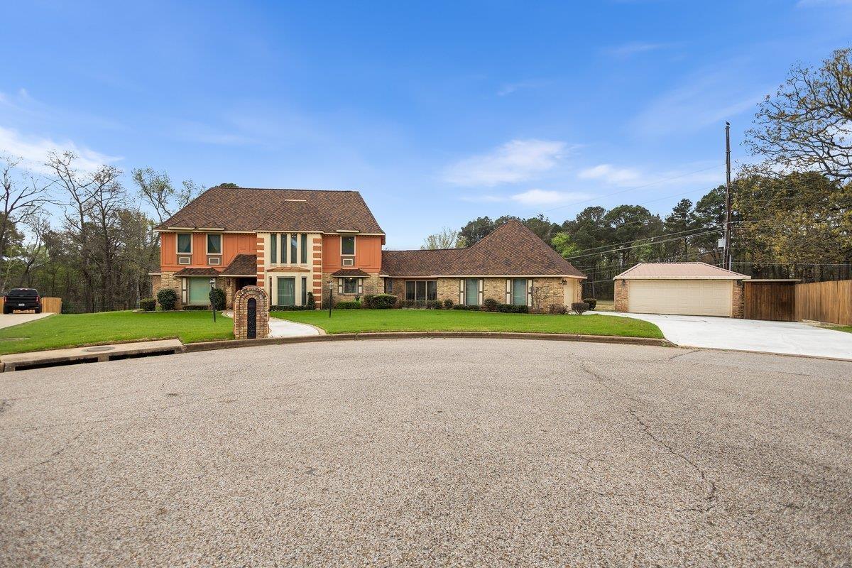 Image 1: View of front facade with a garage, a front lawn, an outdoor structure, a shingled roof, and brick siding, Front Of Structure