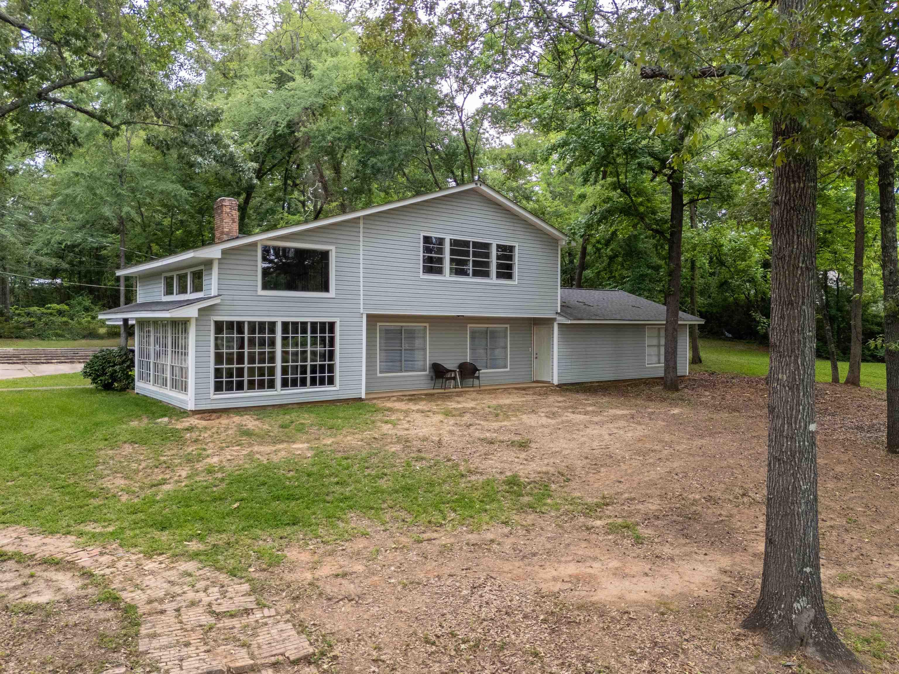 Image 0: Two-story residence featuring light gray siding, a prominent brick chimney, and a screened-in porch with multiple windows, Back Of Structure
