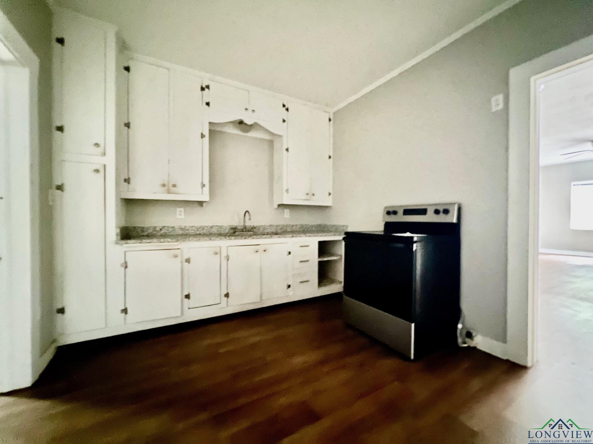 Image 2: Kitchen with electric stove, white cabinets, dark wood finished floors, and light countertops, Kitchen