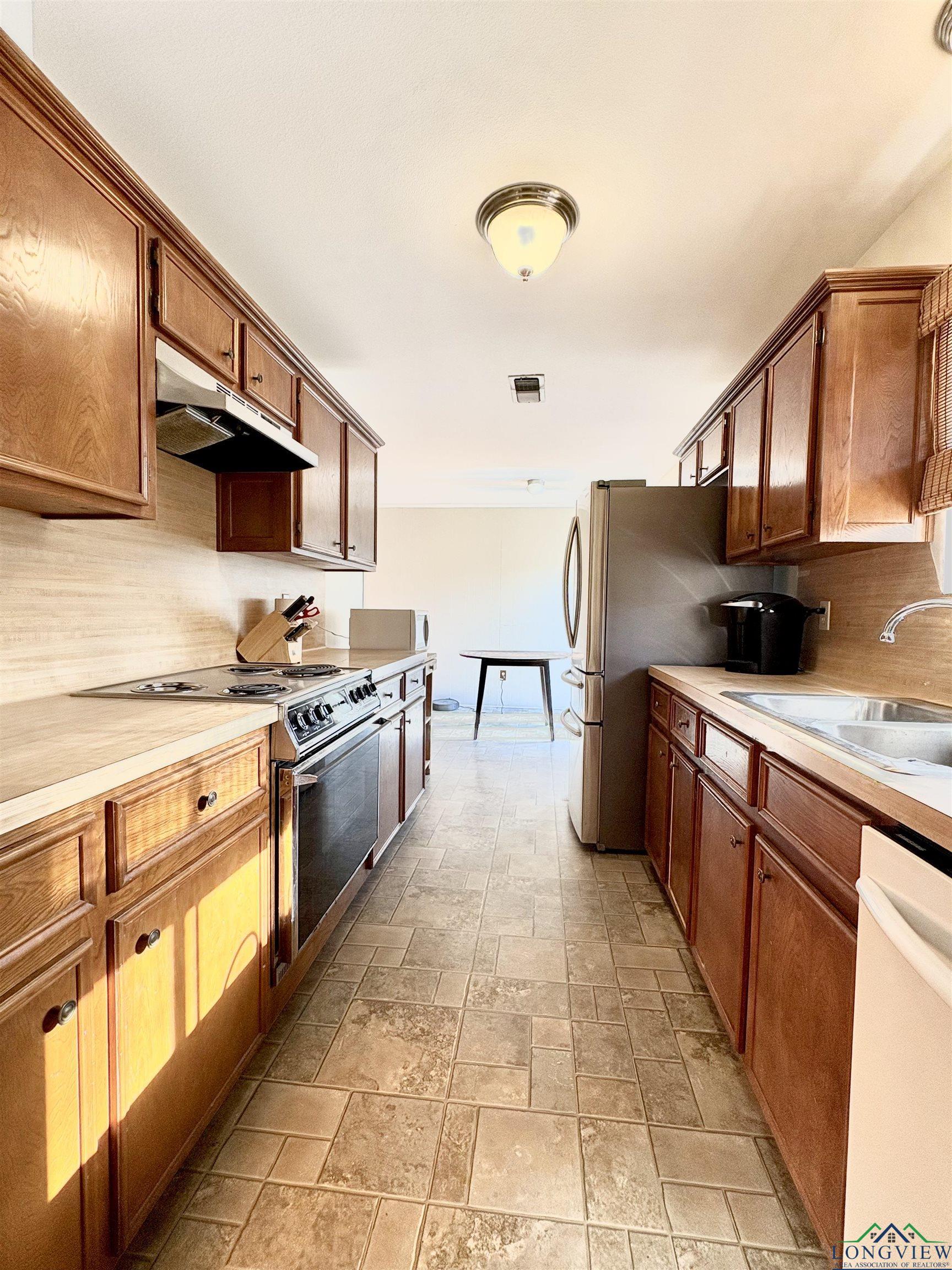 Image 2: Kitchen featuring light countertops, tasteful backsplash, appliances with stainless steel finishes, and under cabinet range hood, Kitchen