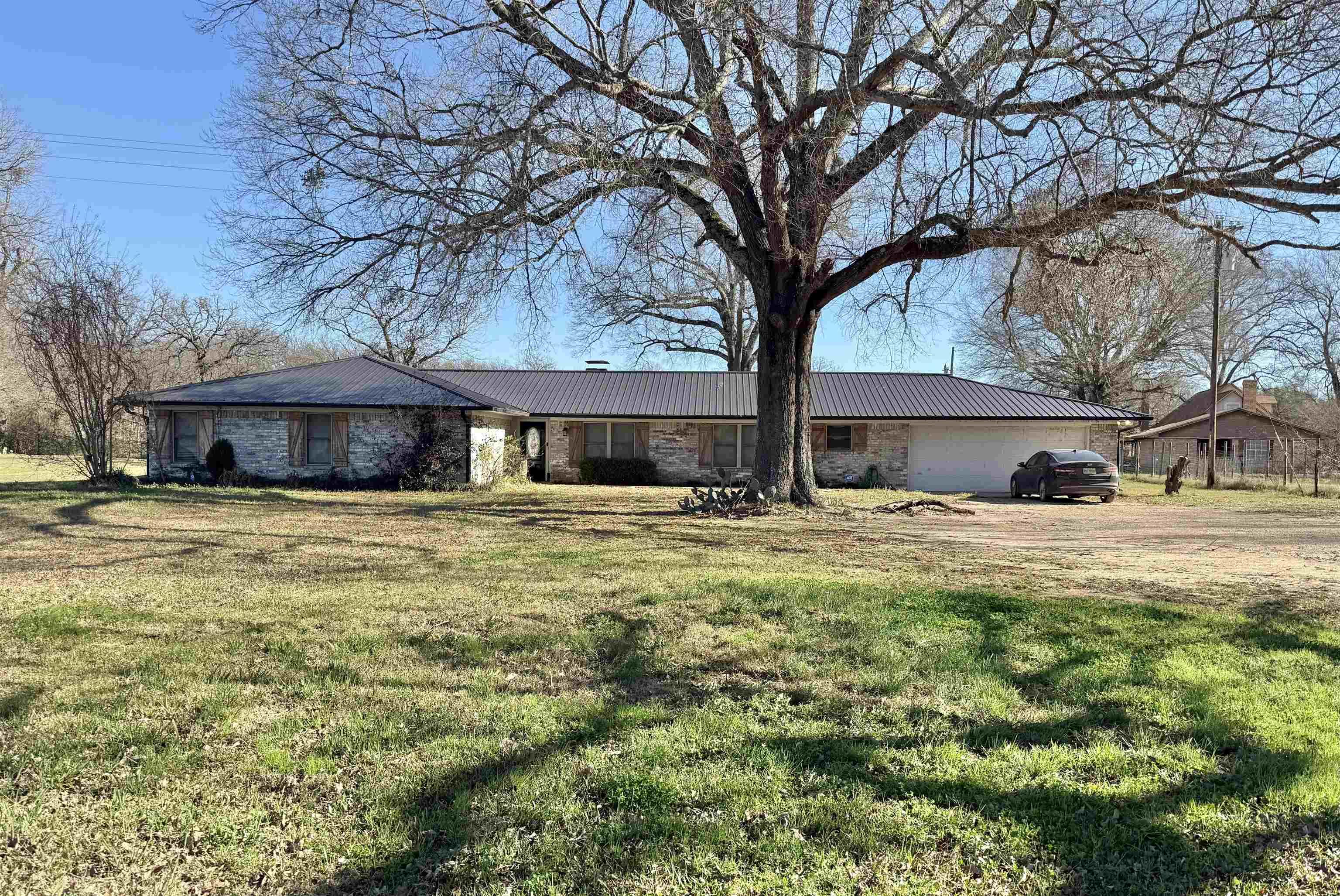 Image 0: Single story home with a front yard, a metal roof, brick siding, and a garage, Front Of Structure