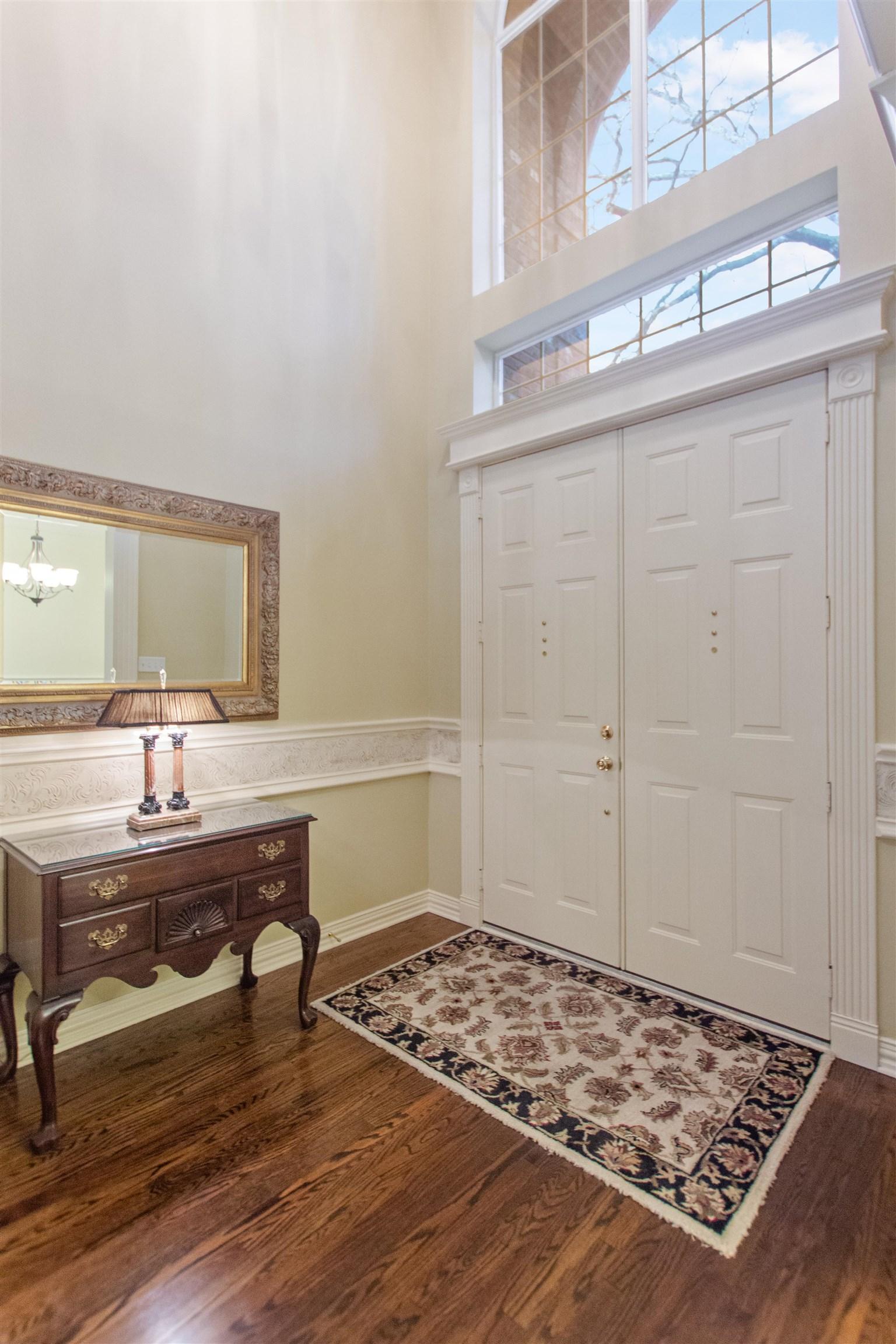 Image 1: Entryway featuring a high ceiling, dark wood-style floors, and suspended lighting, Entrance Foyer