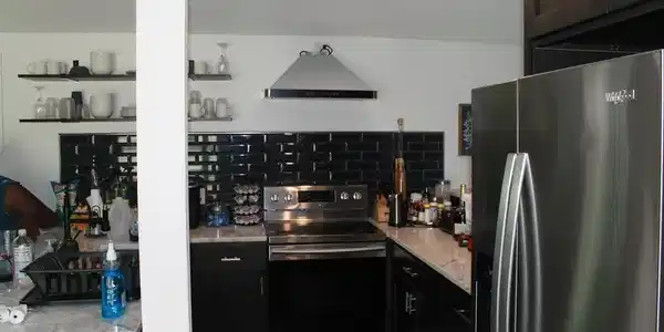 Image 1: Kitchen featuring stainless steel appliances, dark cabinetry with bar pull hardware, black subway tile backsplash, light-toned countertops, and open shelving, Kitchen