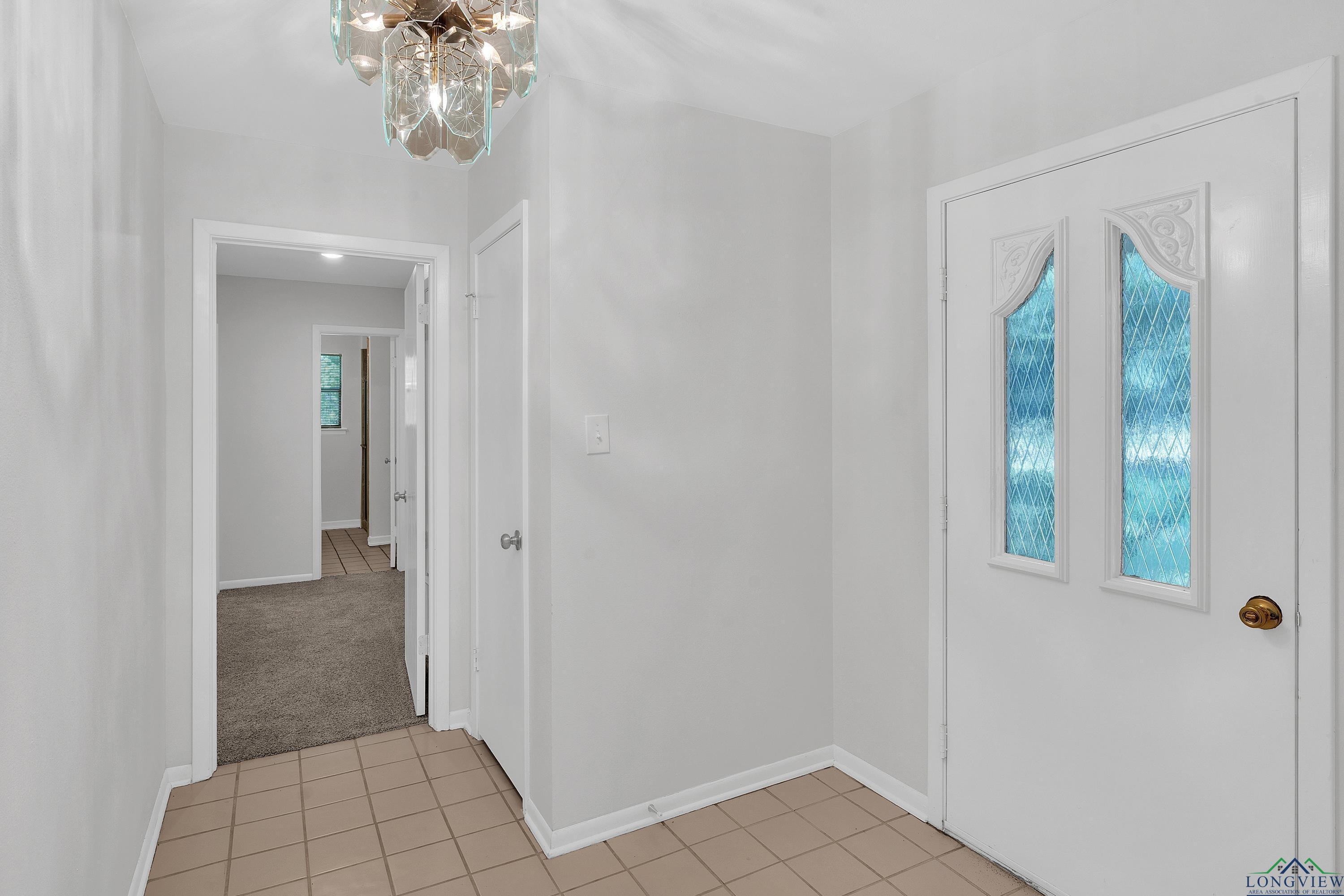 Image 1: Entryway with light tile patterned flooring, light carpet, and a chandelier, Entrance Foyer