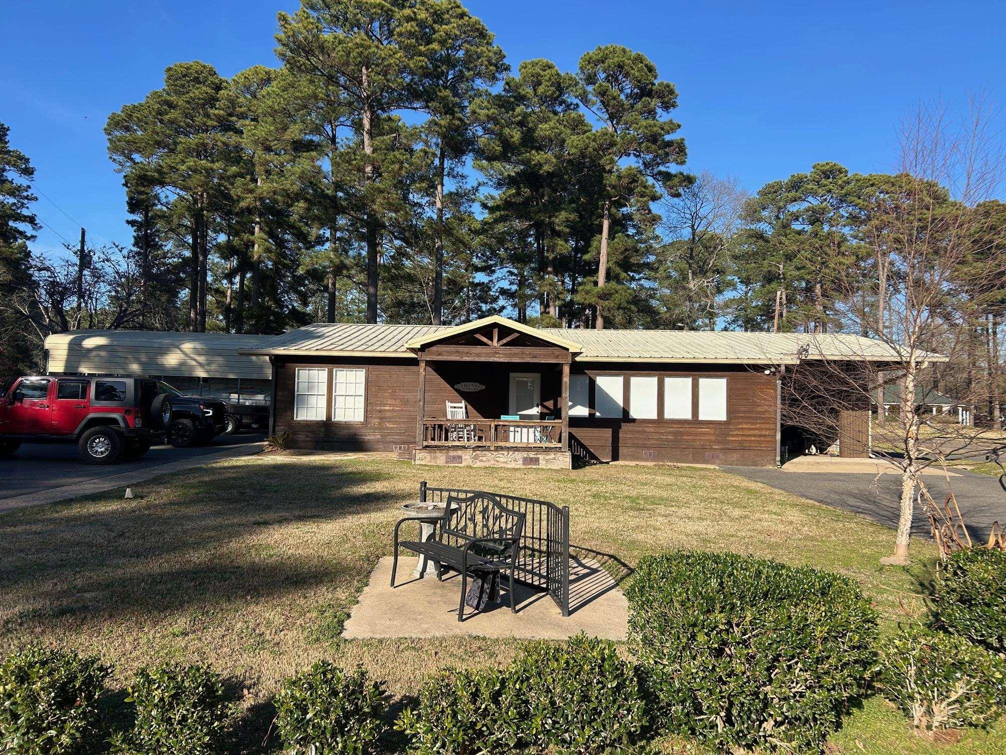 Image 2: View of front of property featuring a metal roof, asphalt driveway, an attached carport, and a front lawn, Front Of Structure
