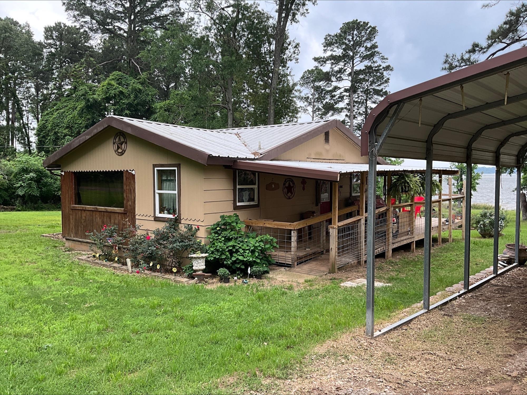 Image 1: Waterfront property featuring a covered porch, metal roof, and an attached carport, Side Of Structure