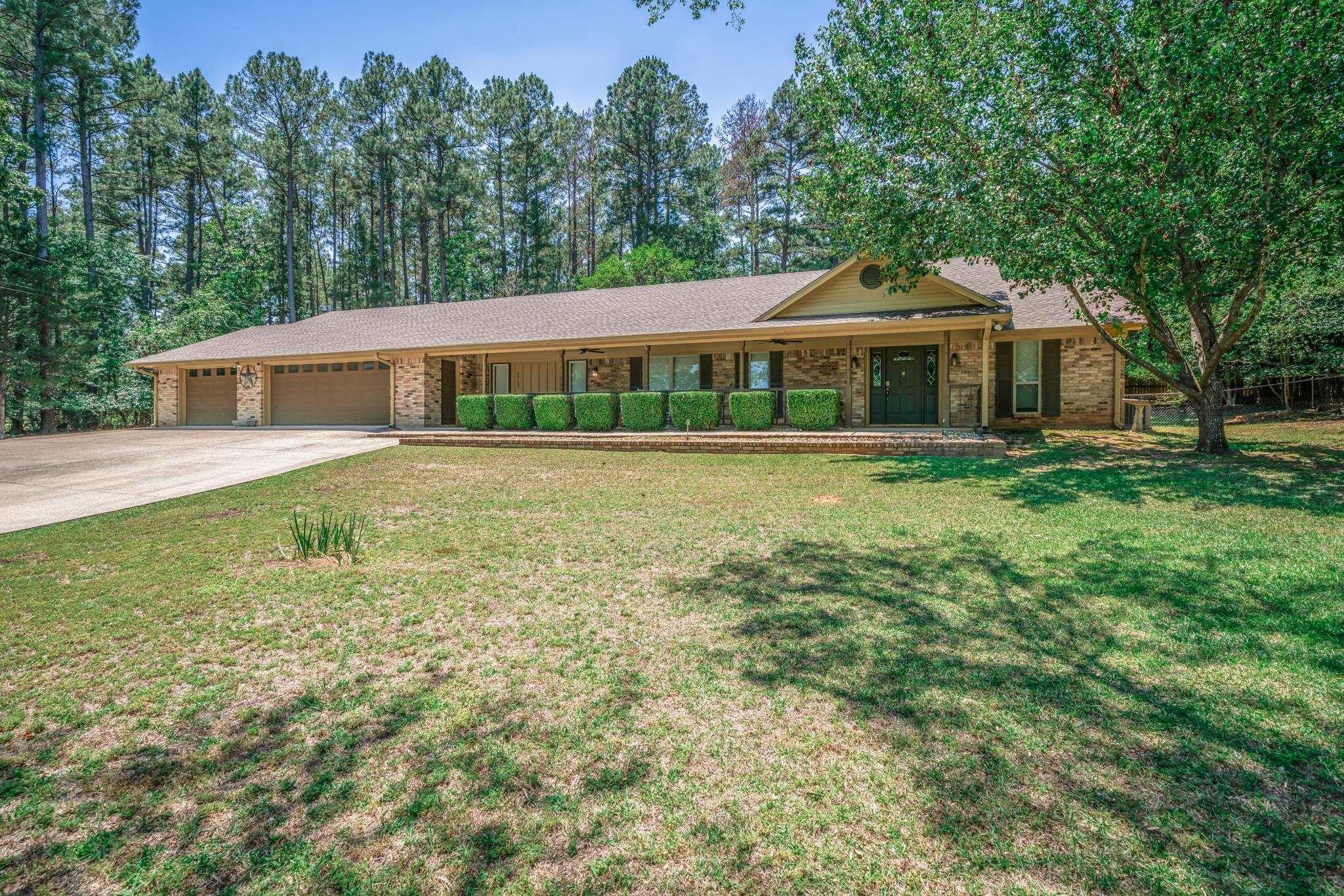 Image 1: Brick exterior with a three-car garage and an extended driveway, Front Of Structure