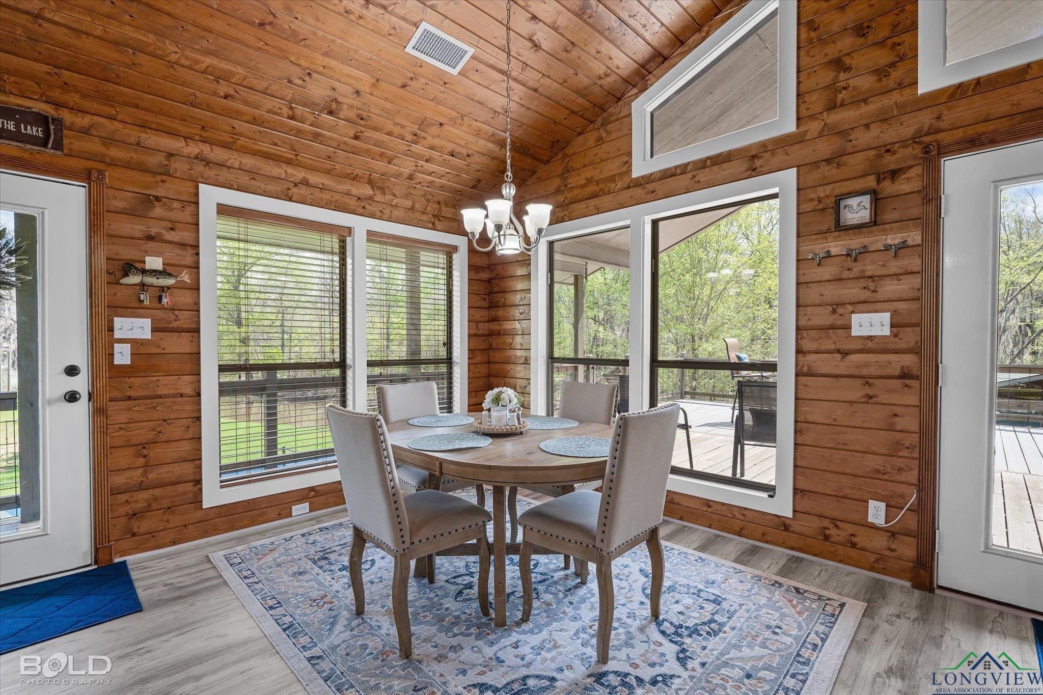 Image 2: Dining space featuring wooden walls, high vaulted ceiling, wooden ceiling, an inviting chandelier, and light wood-type flooring, Dining Area