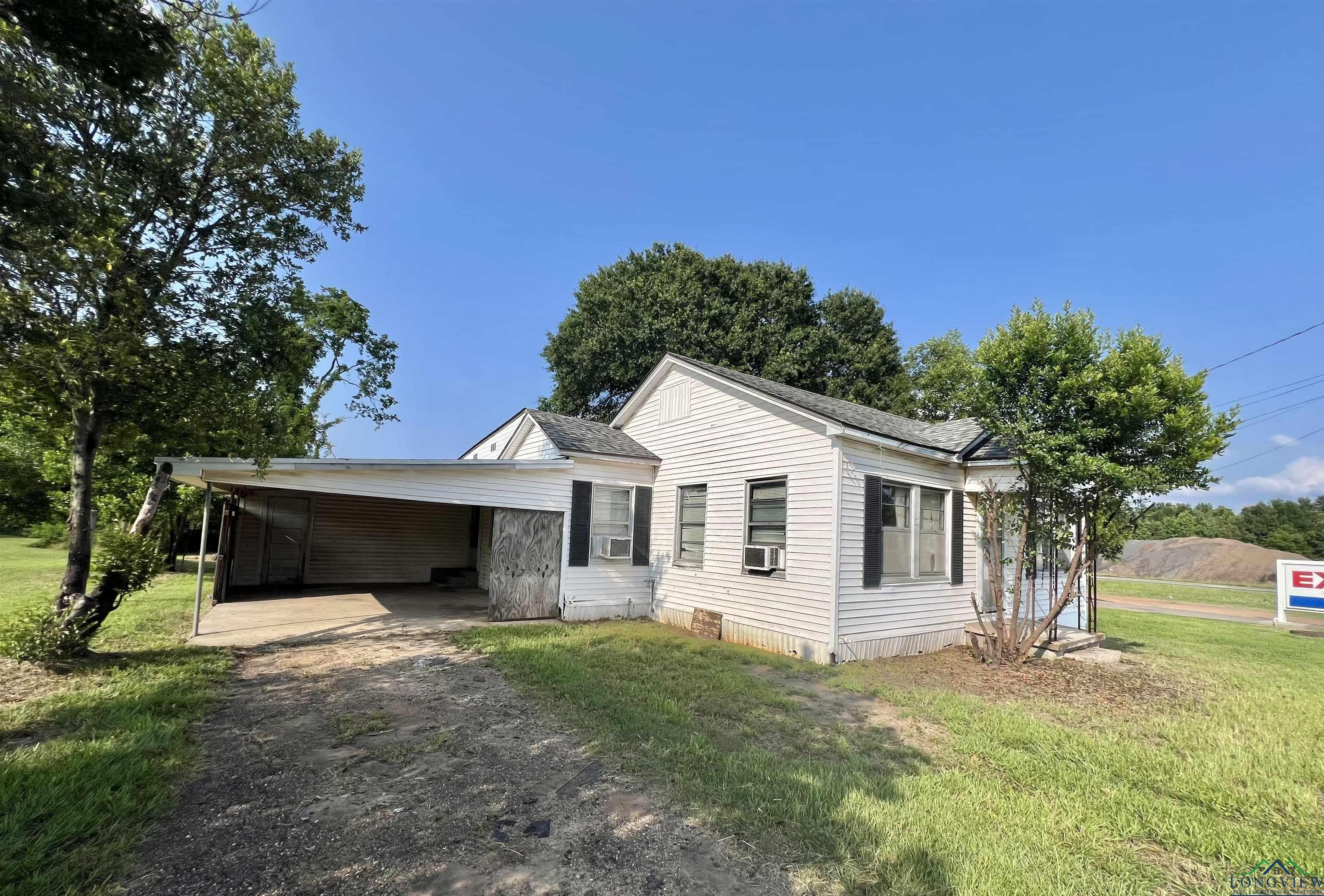 Image 1: View of front facade featuring driveway, an attached carport, a front yard, cooling unit, and roof with shingles, Front Of Structure