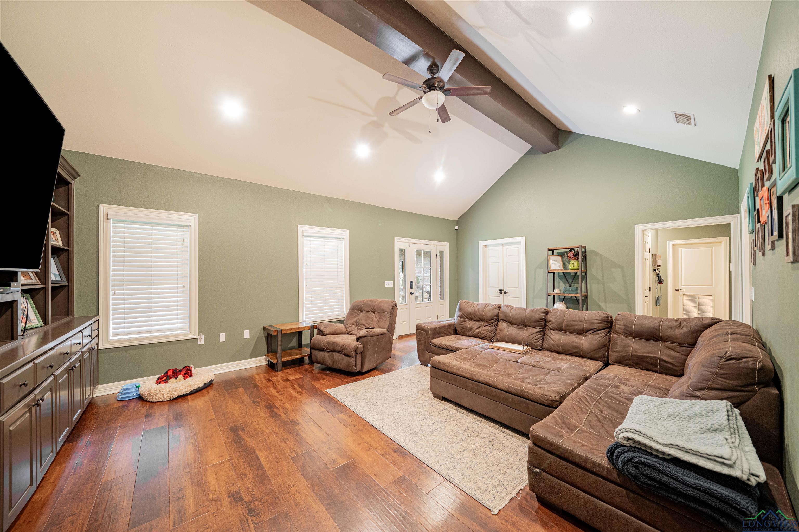 Image 3: Living area with beam ceiling, dark wood-style flooring, a ceiling fan, recessed lighting, and high vaulted ceiling, Living Room