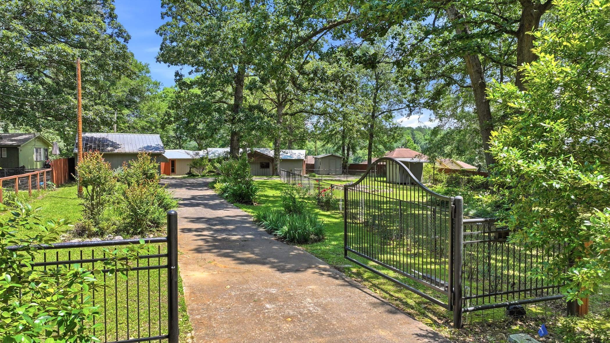Image 2: Gated entry with a paved driveway, surrounded by mature trees and landscaped shrubbery, Front Of Structure