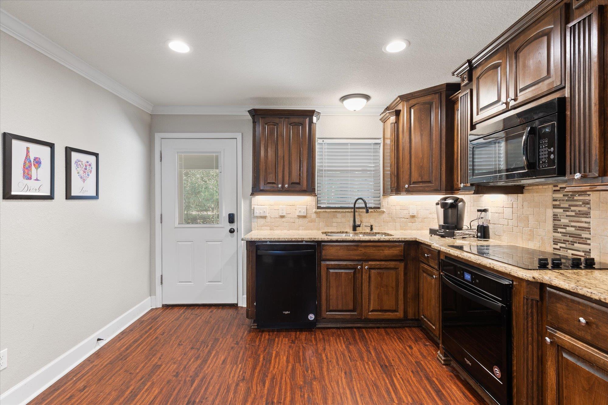 Image 4: Kitchen featuring wood-finish flooring, dark wood cabinetry, light granite countertops, a tiled backsplash, and recessed lighting, Kitchen