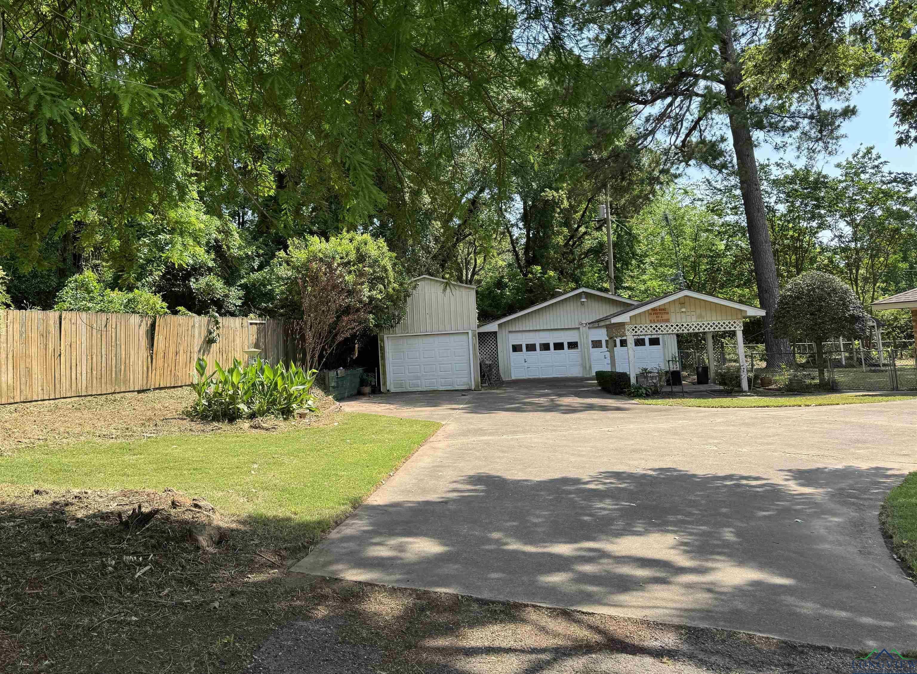 Image 1: View of front of home featuring a garage, an outbuilding, and view of wooded area, Front Of Structure