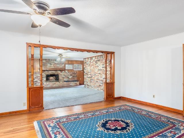 Image 3: Unfurnished living room with wood finished floors, a fireplace, and brick wall, Living Room