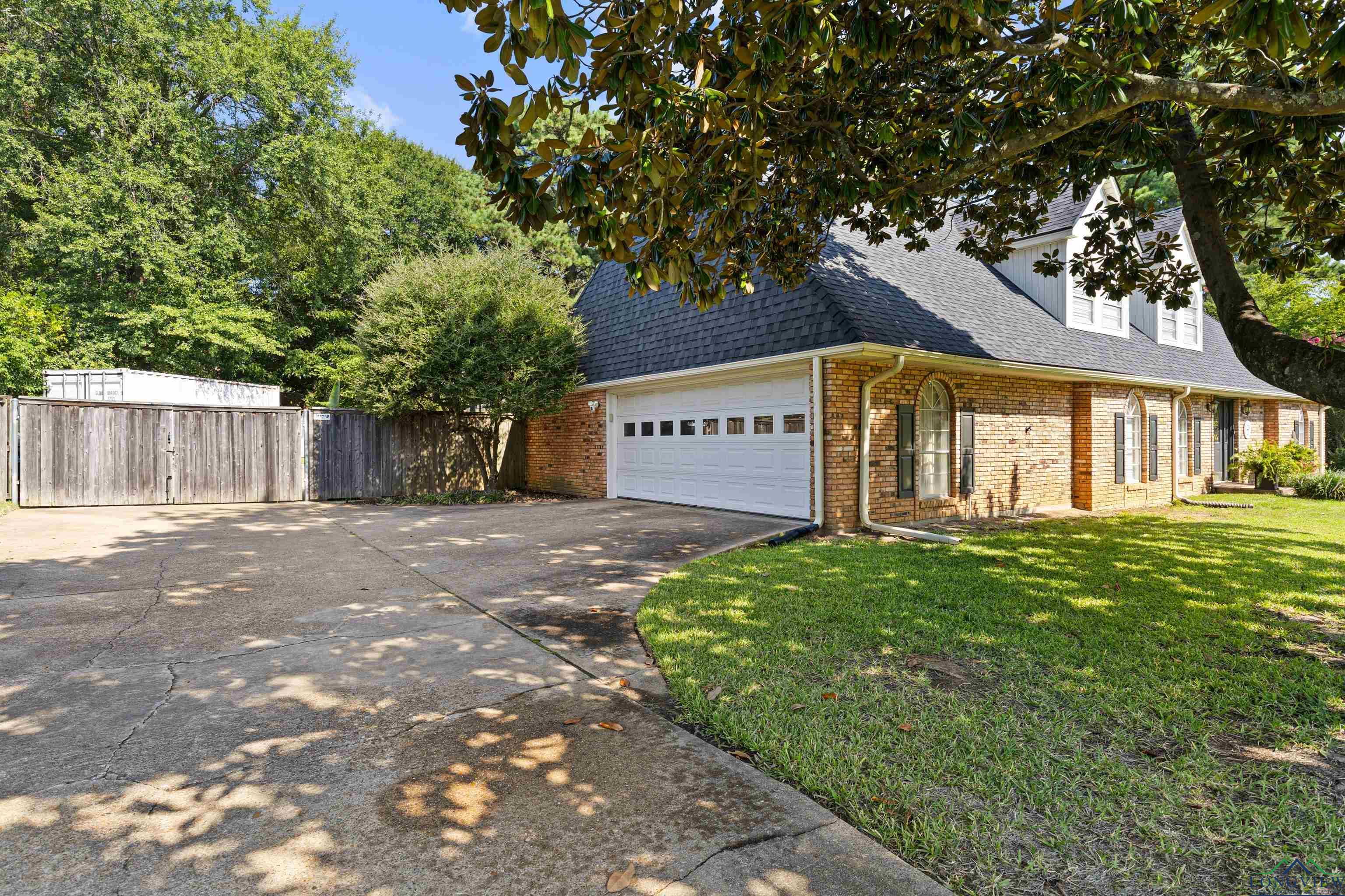 Image 3: View of property exterior with driveway, roof with shingles, brick siding, and a garage, Side Of Structure
