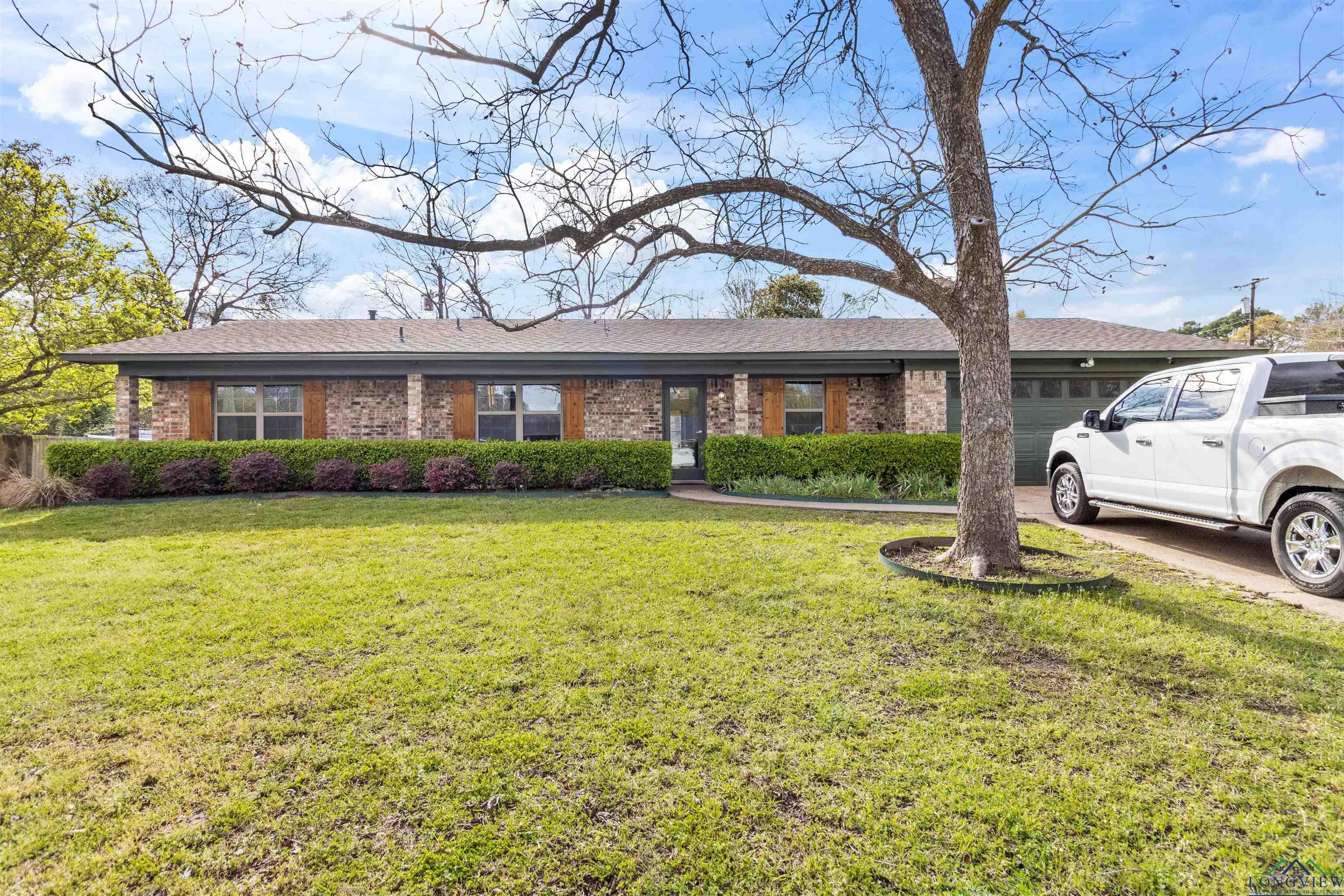 Image 0: Single story home with brick siding, a front yard, a garage, and driveway, Front Of Structure