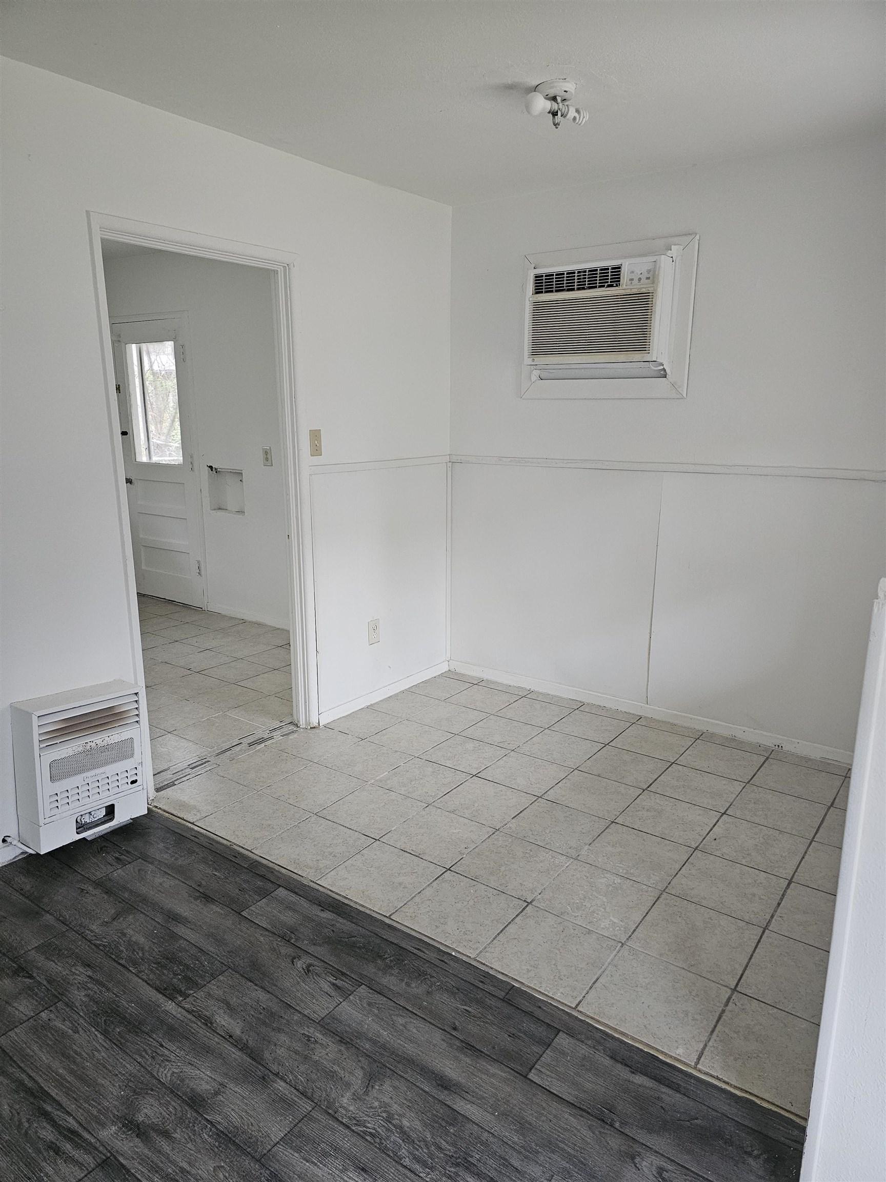 Image 2: Empty room with heating unit, wood finished floors, and a wall mounted AC, Other