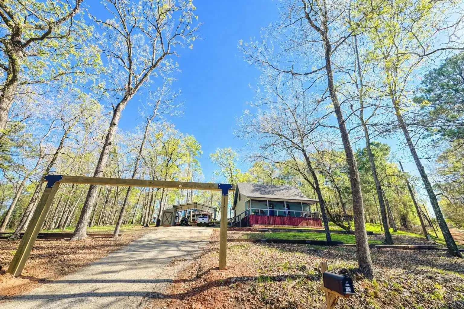 Image 0: View of front facade featuring a carport, driveway, and a wooden deck, Front Of Structure