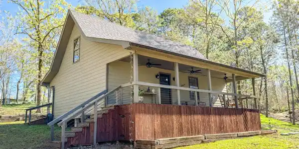 Image 2: View of side of home with ceiling fan, a shingled roof, a porch, and a lawn, Side Of Structure