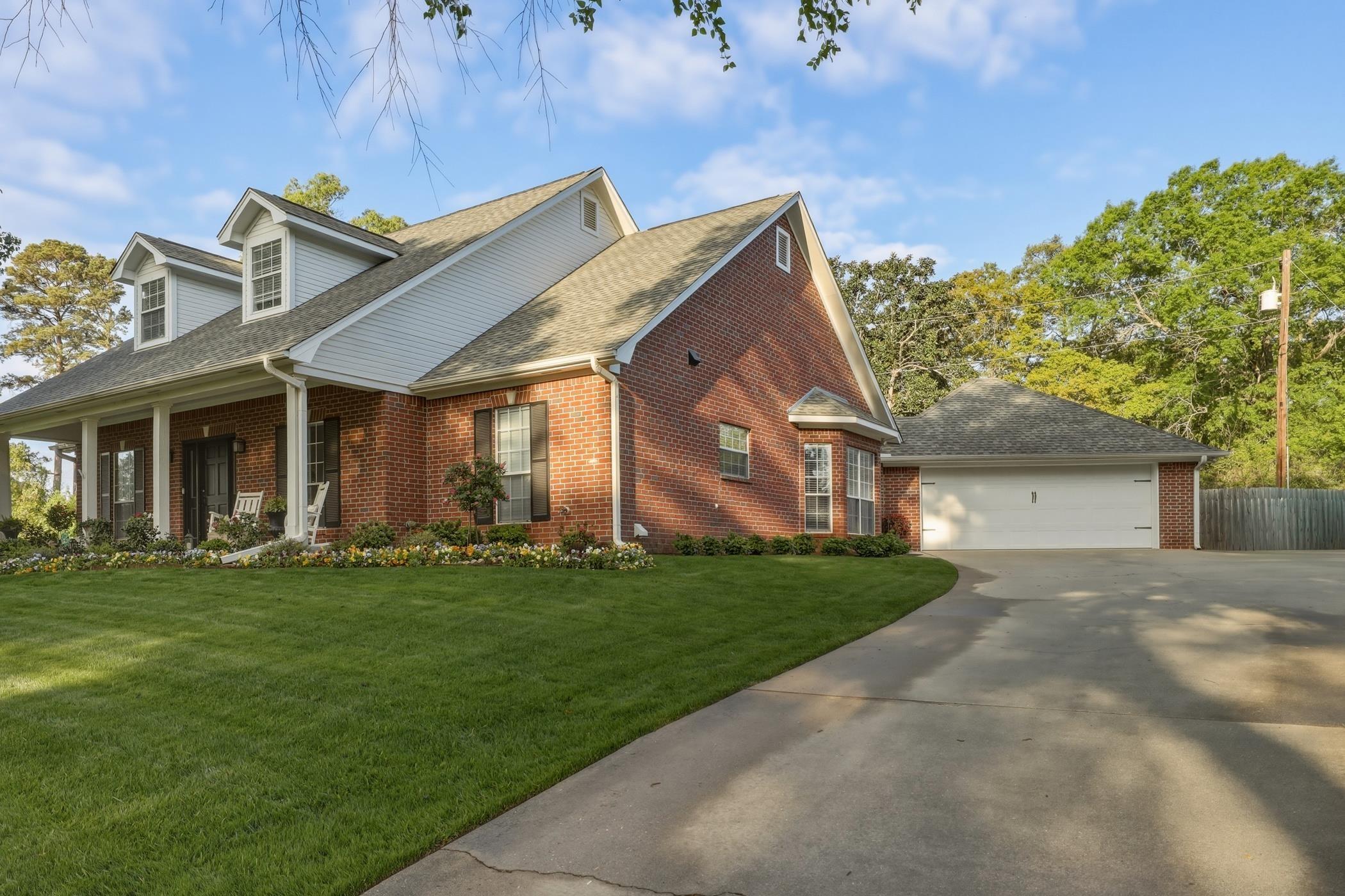 Image 2: View of front facade featuring brick siding, a shingled roof, a front lawn, and a porch, Front Of Structure