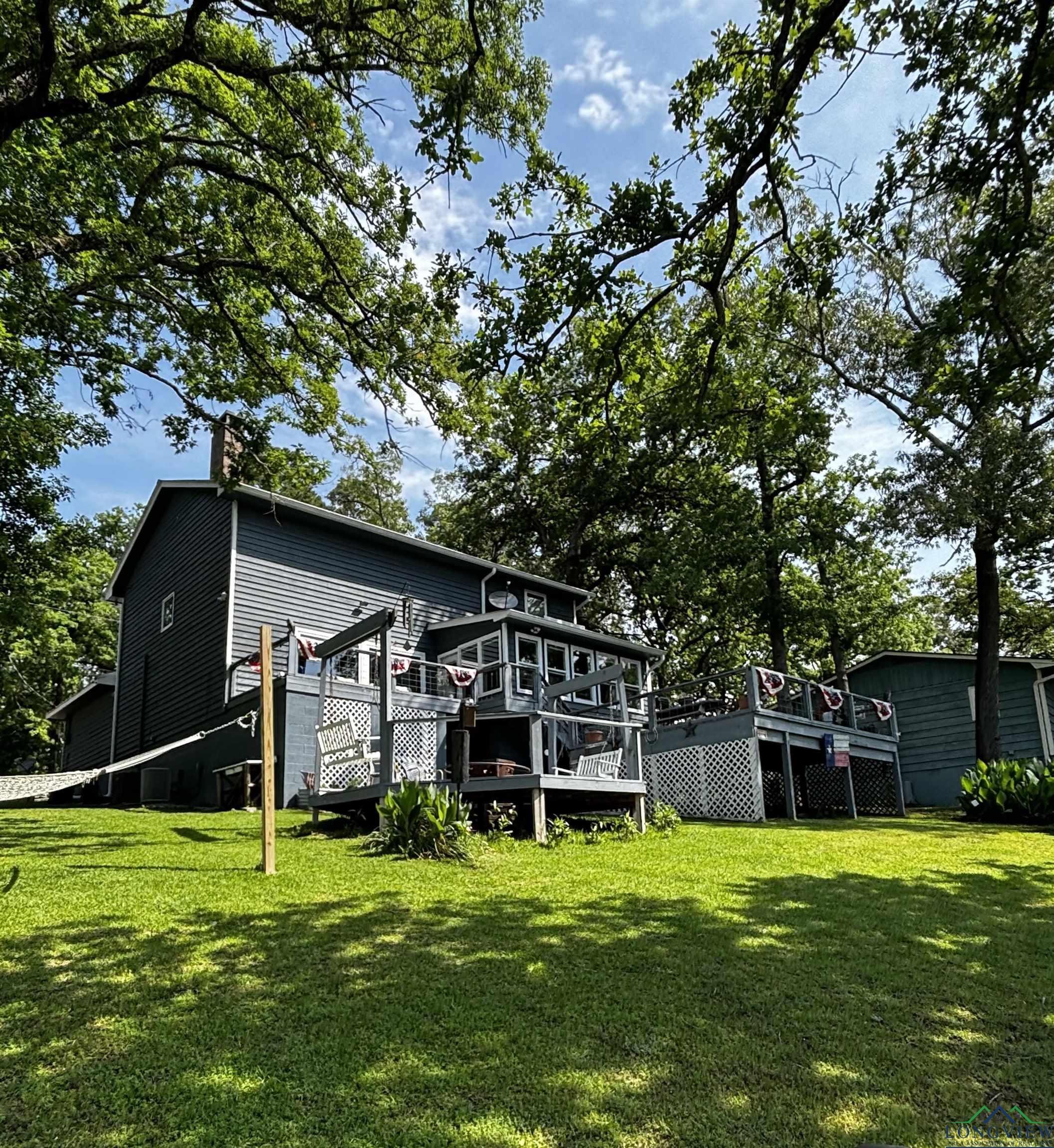 Image 0: Back of house featuring a lawn, a chimney, and a wooden deck, Back Of Structure