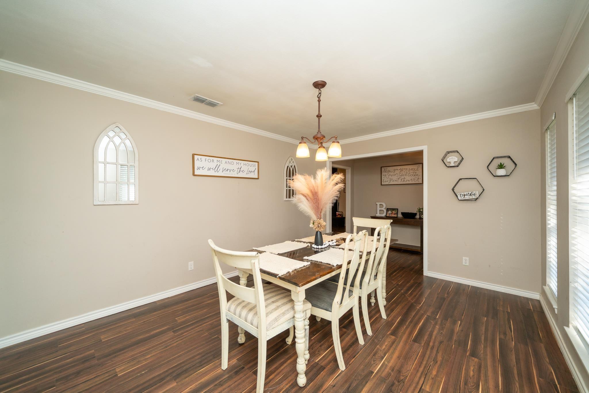 Image 3: Dining area with hanging lights, dark wood finished floors, and ornamental molding, Dining Area