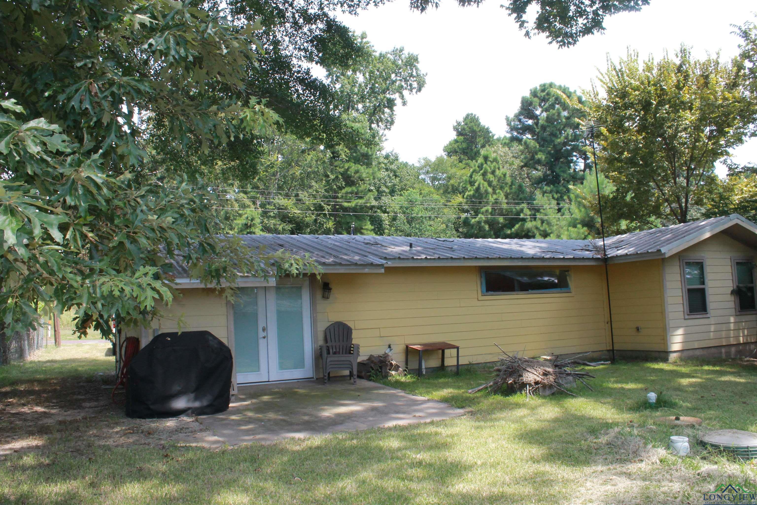 Image 1: Back of house with a metal roof, a lawn, and a patio area, Back Of Structure