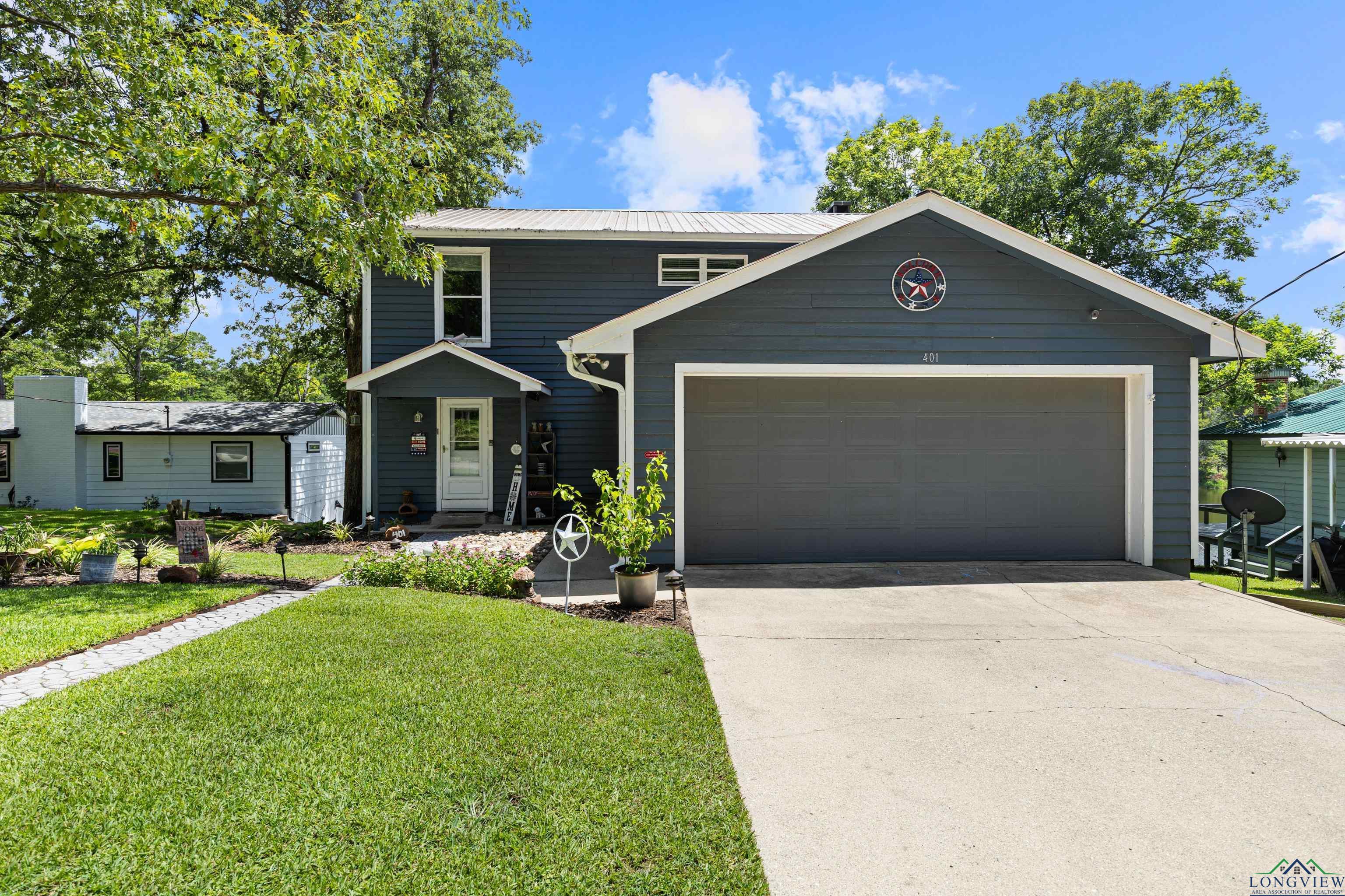 Image 2: View of front of home with concrete driveway, a front lawn, a metal roof, and an attached garage, Front Of Structure