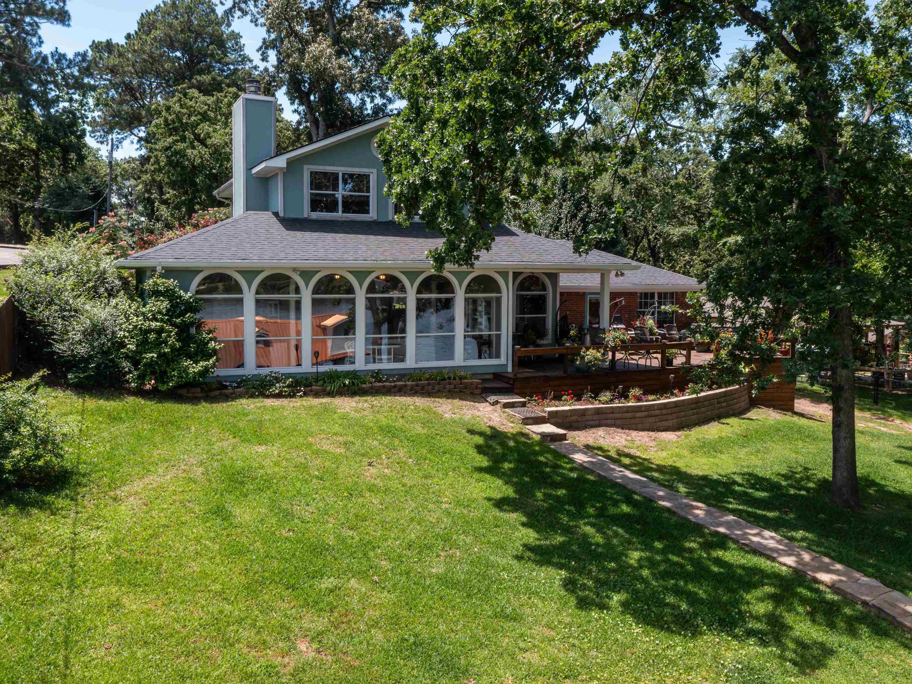 Image 0: Back of property with a yard, roof with shingles, a chimney, a wooden deck, and view of scattered trees, Lakefront of home