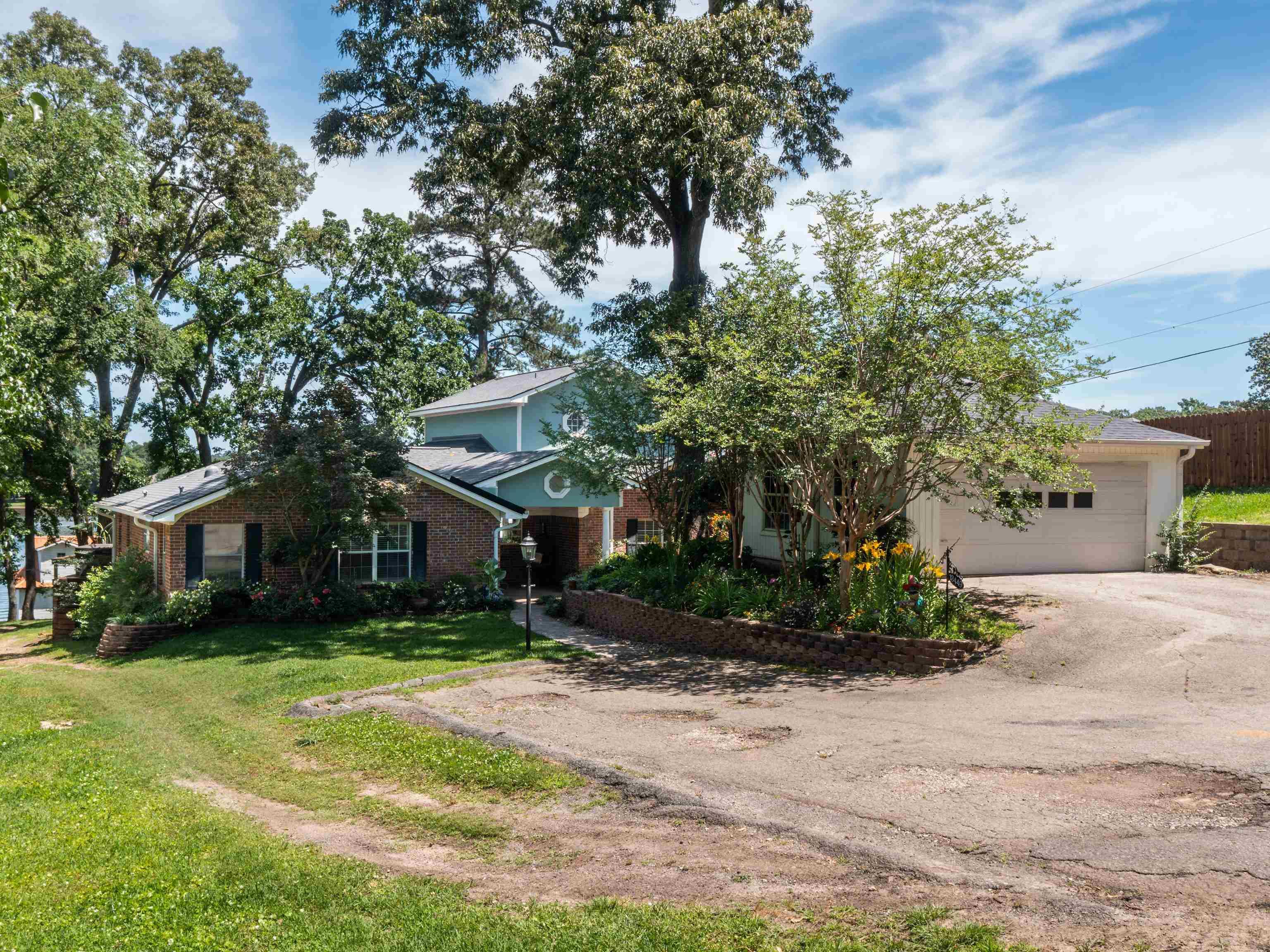 Image 3: Obstructed view of property with asphalt driveway, brick siding, a front yard, and an attached garage, Front Of Structure