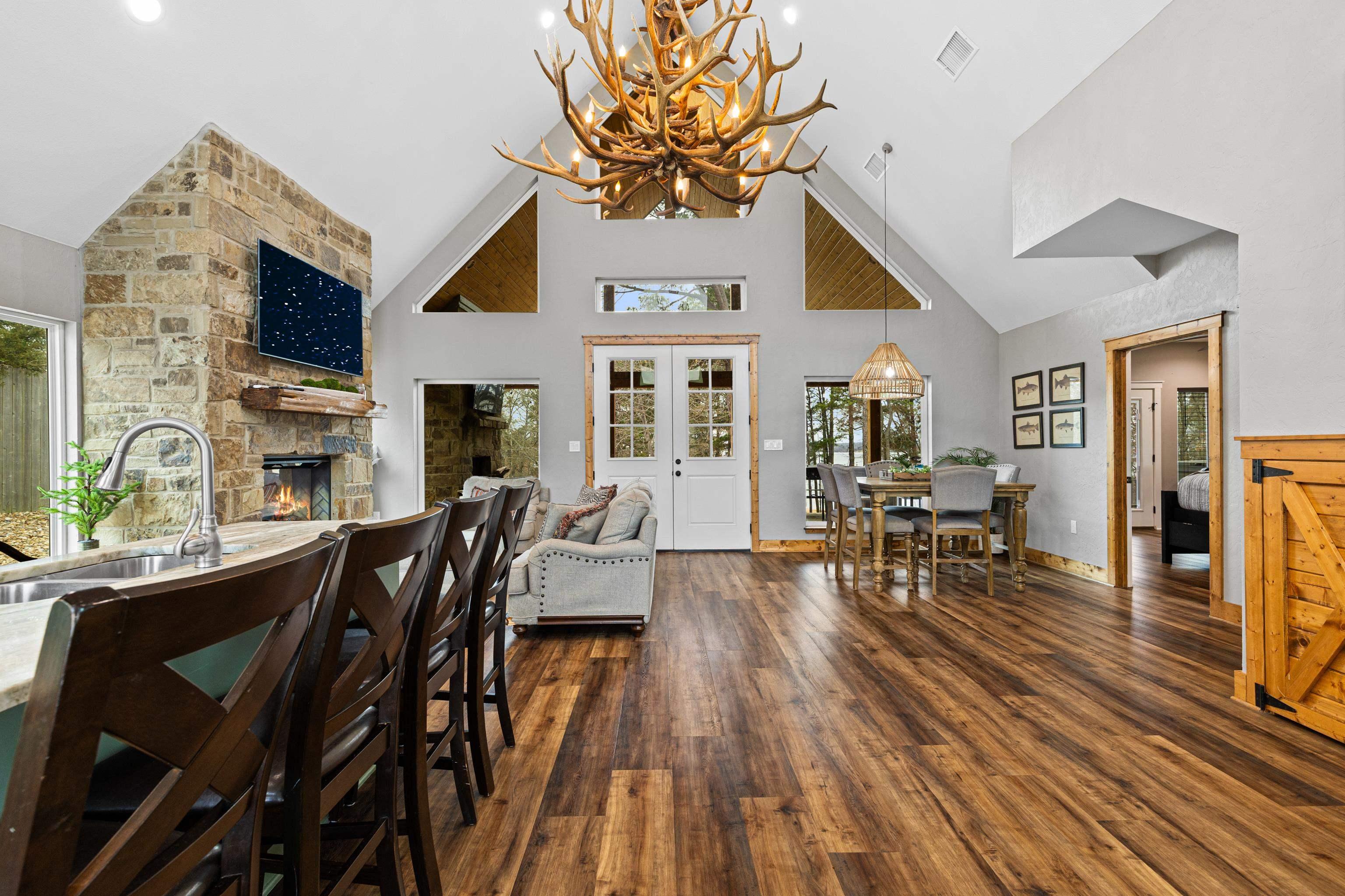 Image 3: Dining area with dark wood finished floors, a stone fireplace, a chandelier, and vaulted ceiling, Dining Area