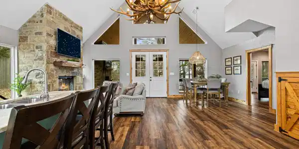 Image 3: Dining area with dark wood finished floors, a stone fireplace, a chandelier, and vaulted ceiling, Dining Area