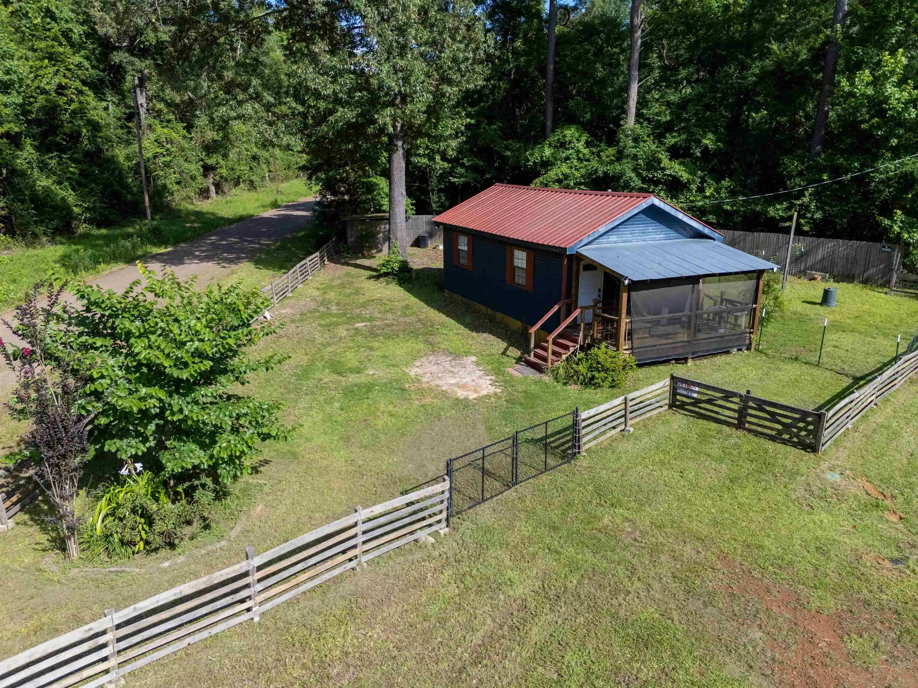 Image 0: Blue exterior with a red metal roof and a screened-in porch, Aerial View