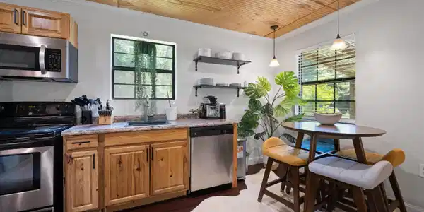 Image 3: Kitchen area featuring wood-finish cabinetry, stainless steel appliances, and a wood-panel ceiling, Kitchen