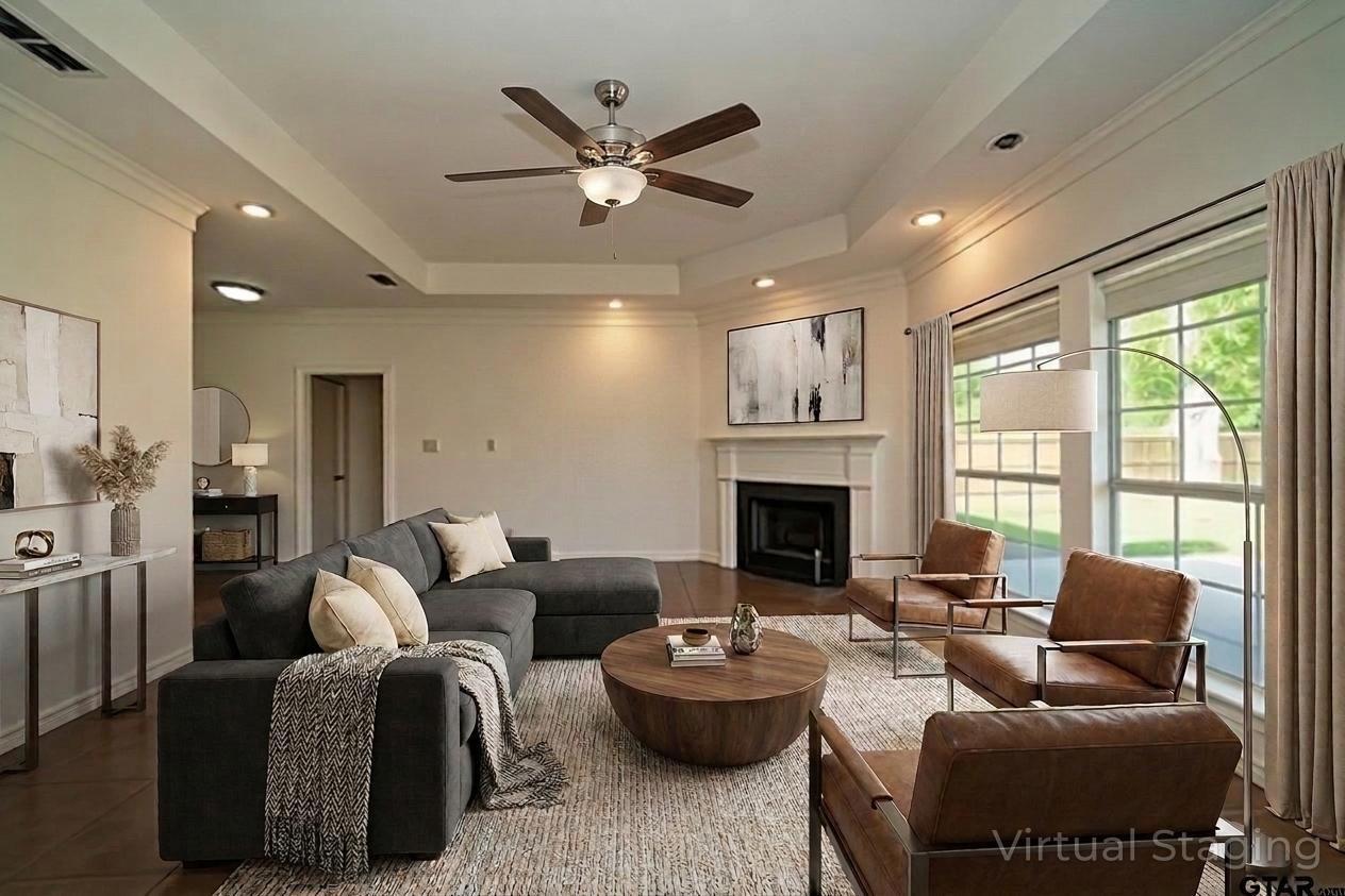 Image 3: Living area featuring a fireplace with a white mantel, tray ceiling with a fan, recessed lighting, and large windows with blinds and drapes, Living Room