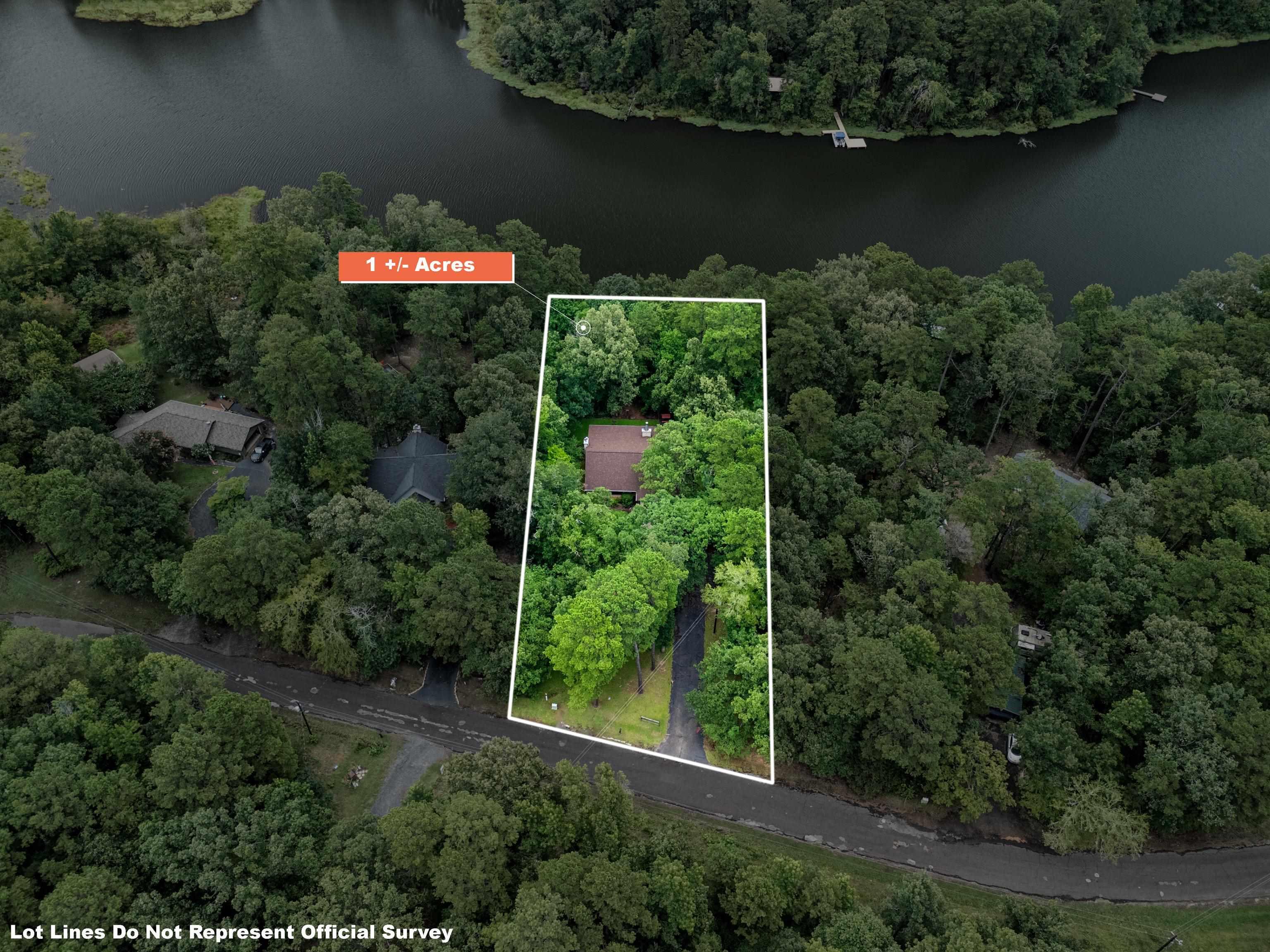 Image 3: Wooded 1+ acre lot featuring a single-story residence, a paved driveway, and a natural water body border, Aerial View