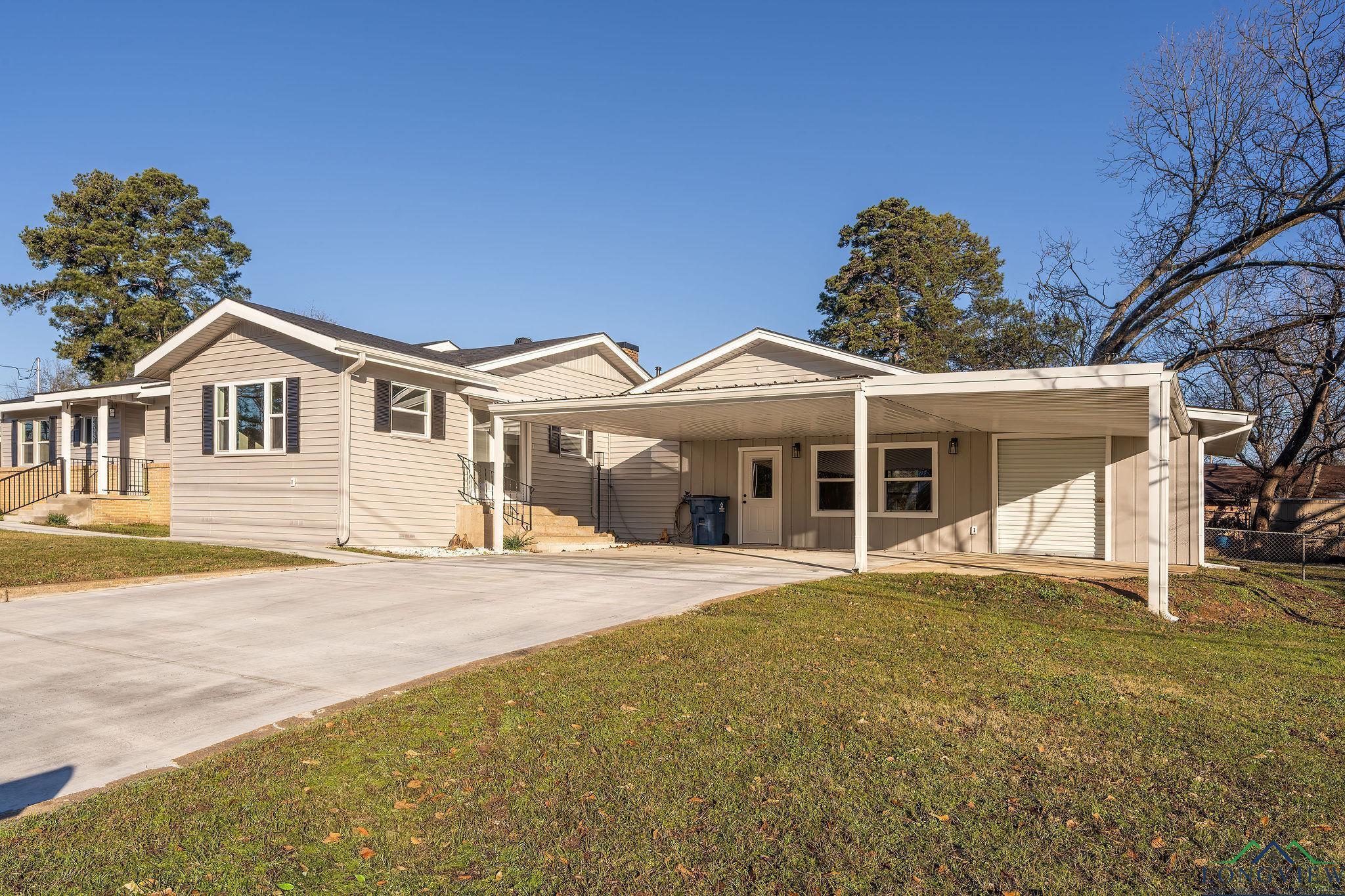 Image 1: Ranch-style home featuring a front yard, board and batten siding, a carport, and driveway, Front Of Structure