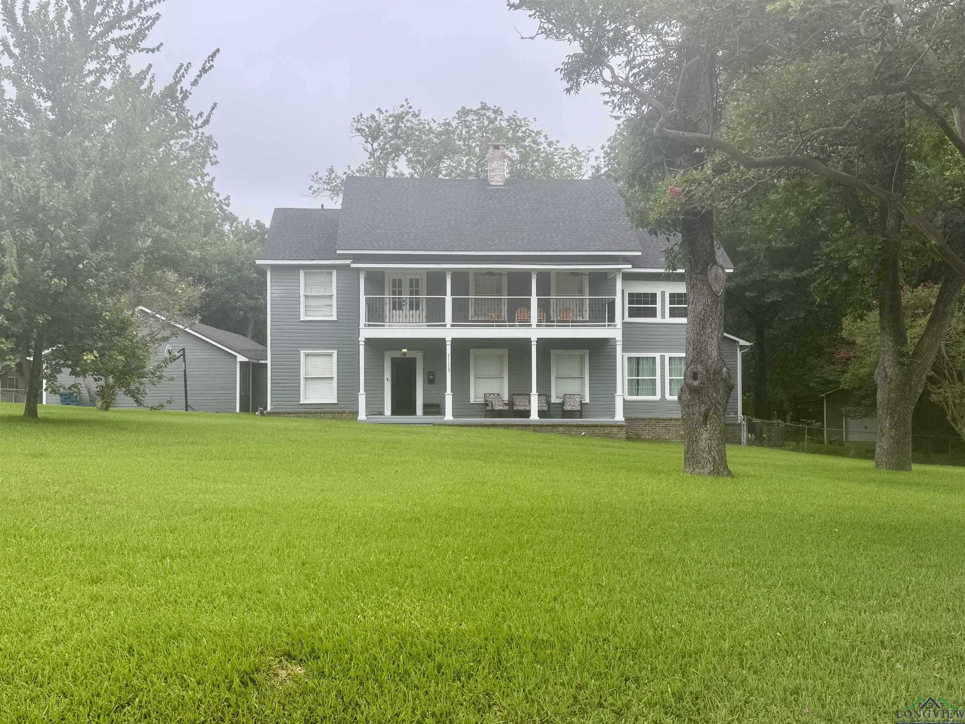 Image 2: Back of property with a lawn, a chimney, a balcony, and a shingled roof, Back Of Structure