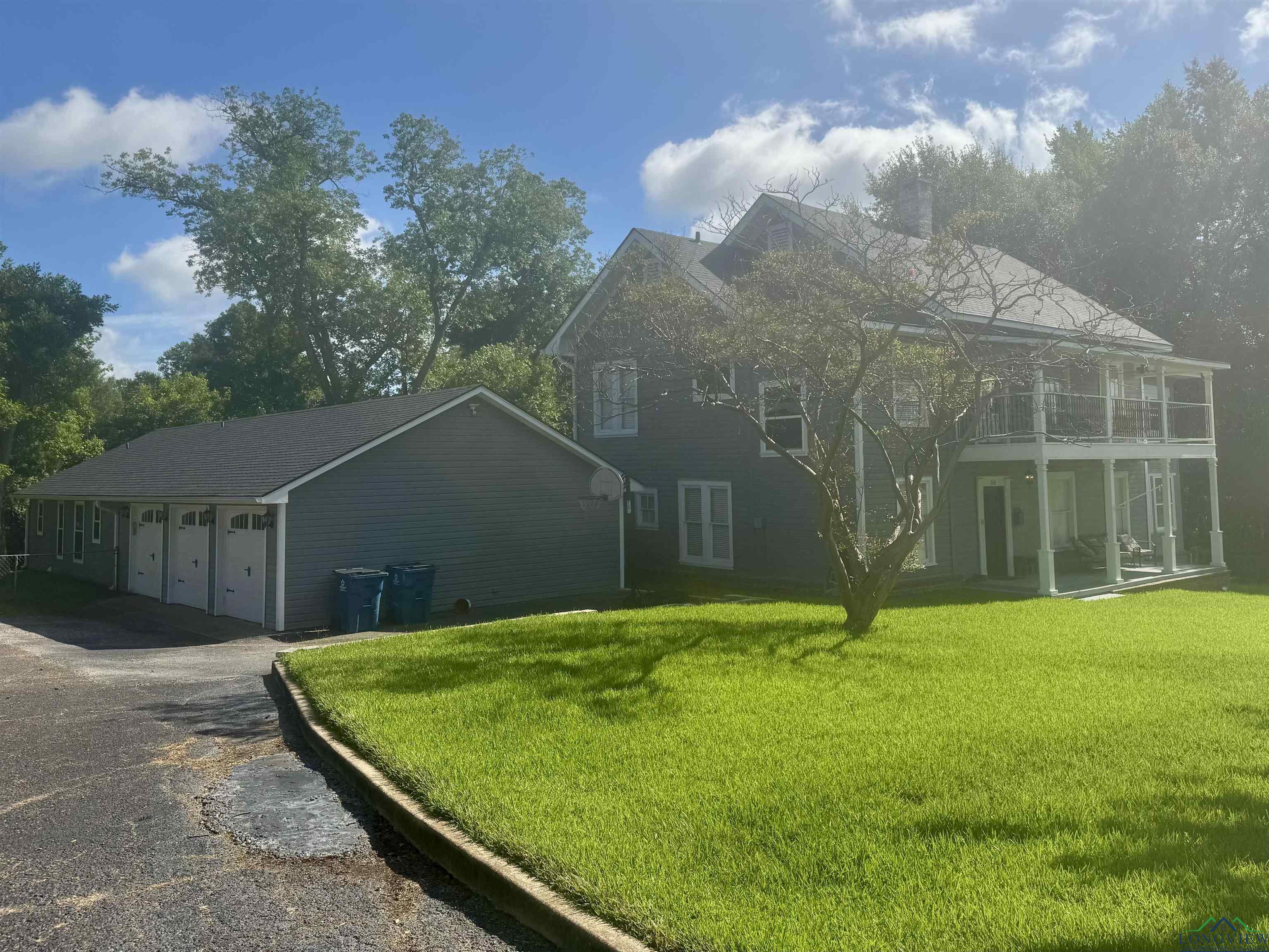 Image 3: View of side of home featuring driveway, a yard, and a garage, Side Of Structure