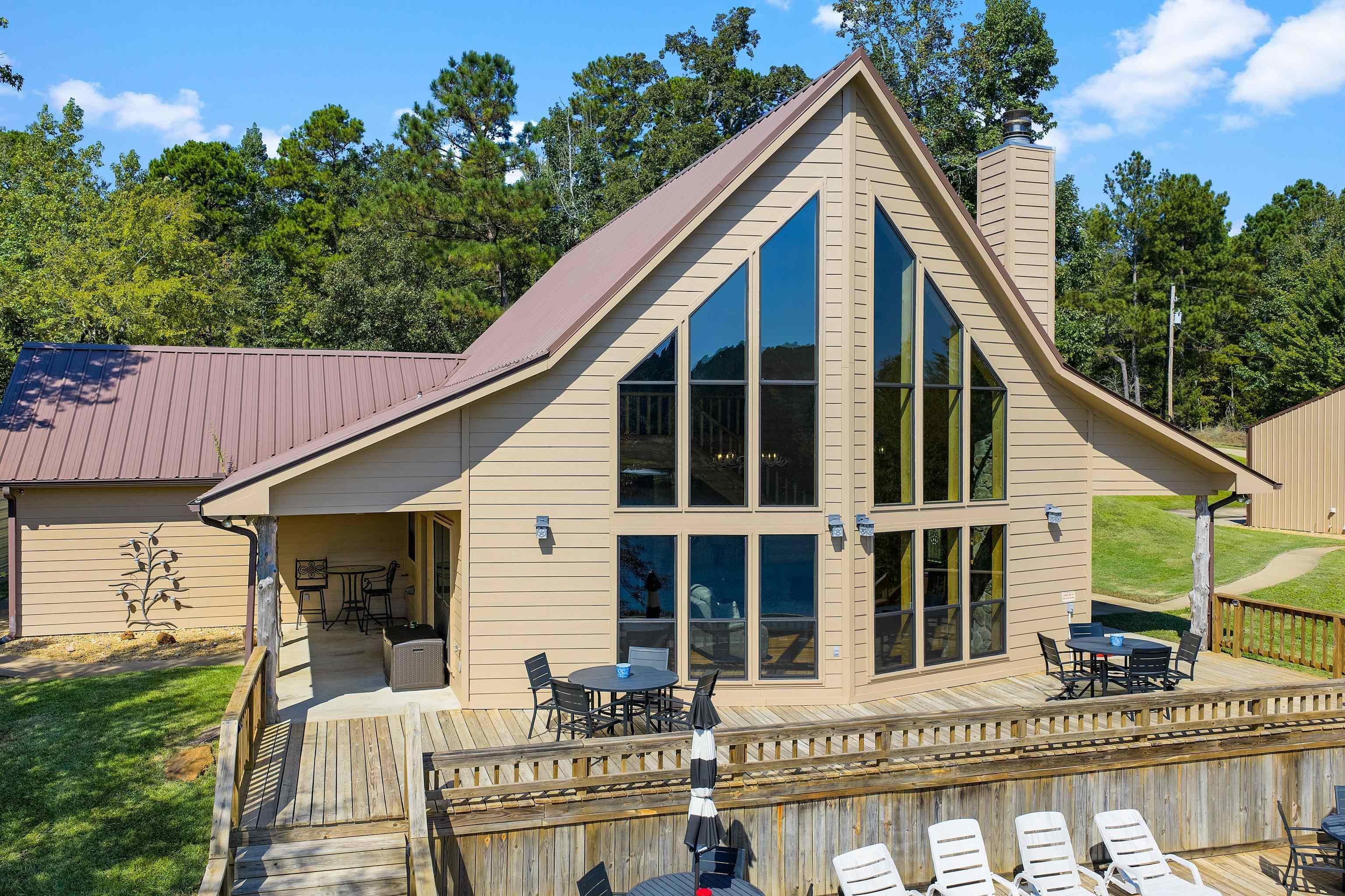 Image 2: Back of property featuring outdoor dining area, a wooden deck, and a chimney